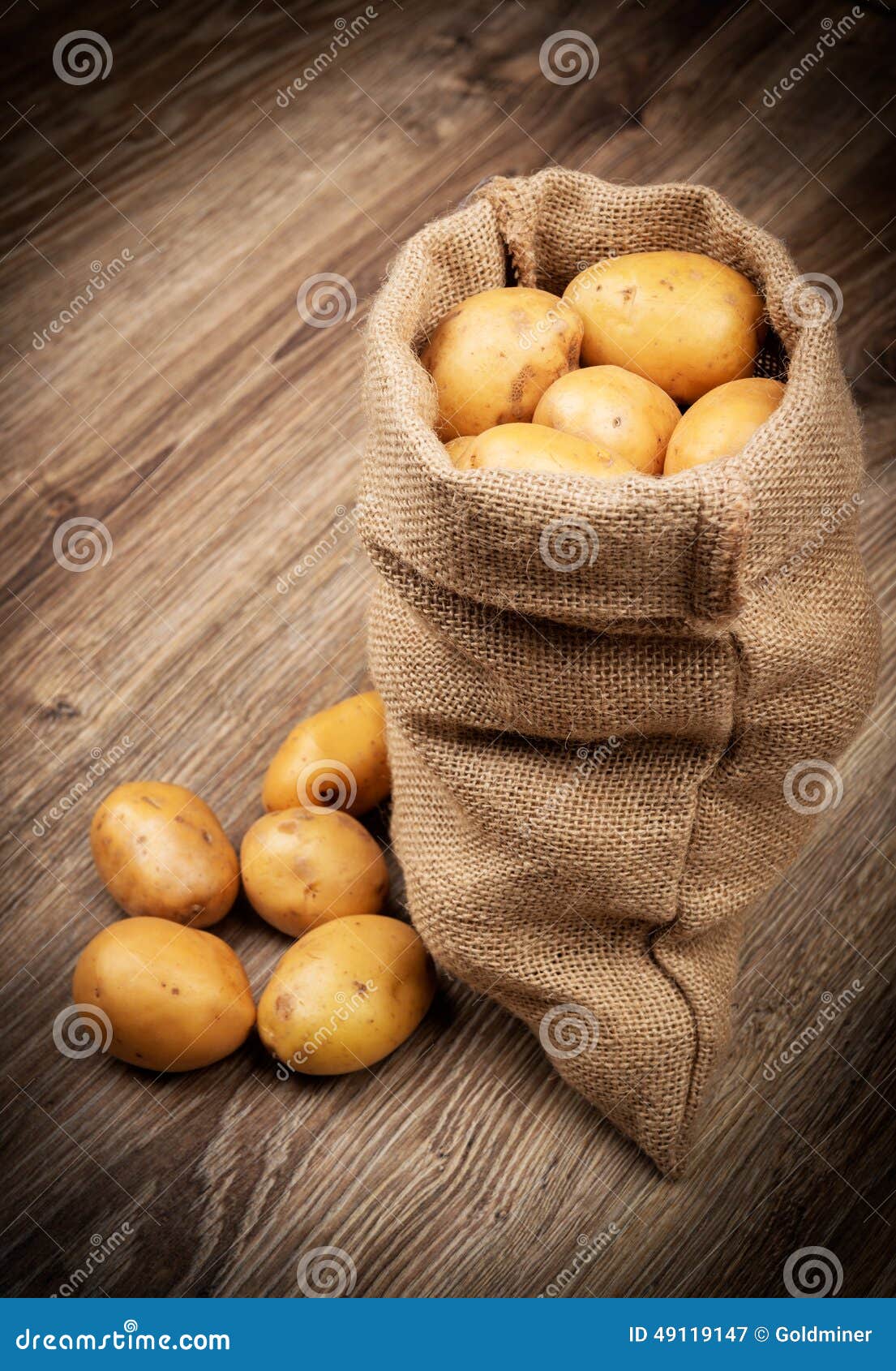 Batatas cruas no saco no fundo de madeira