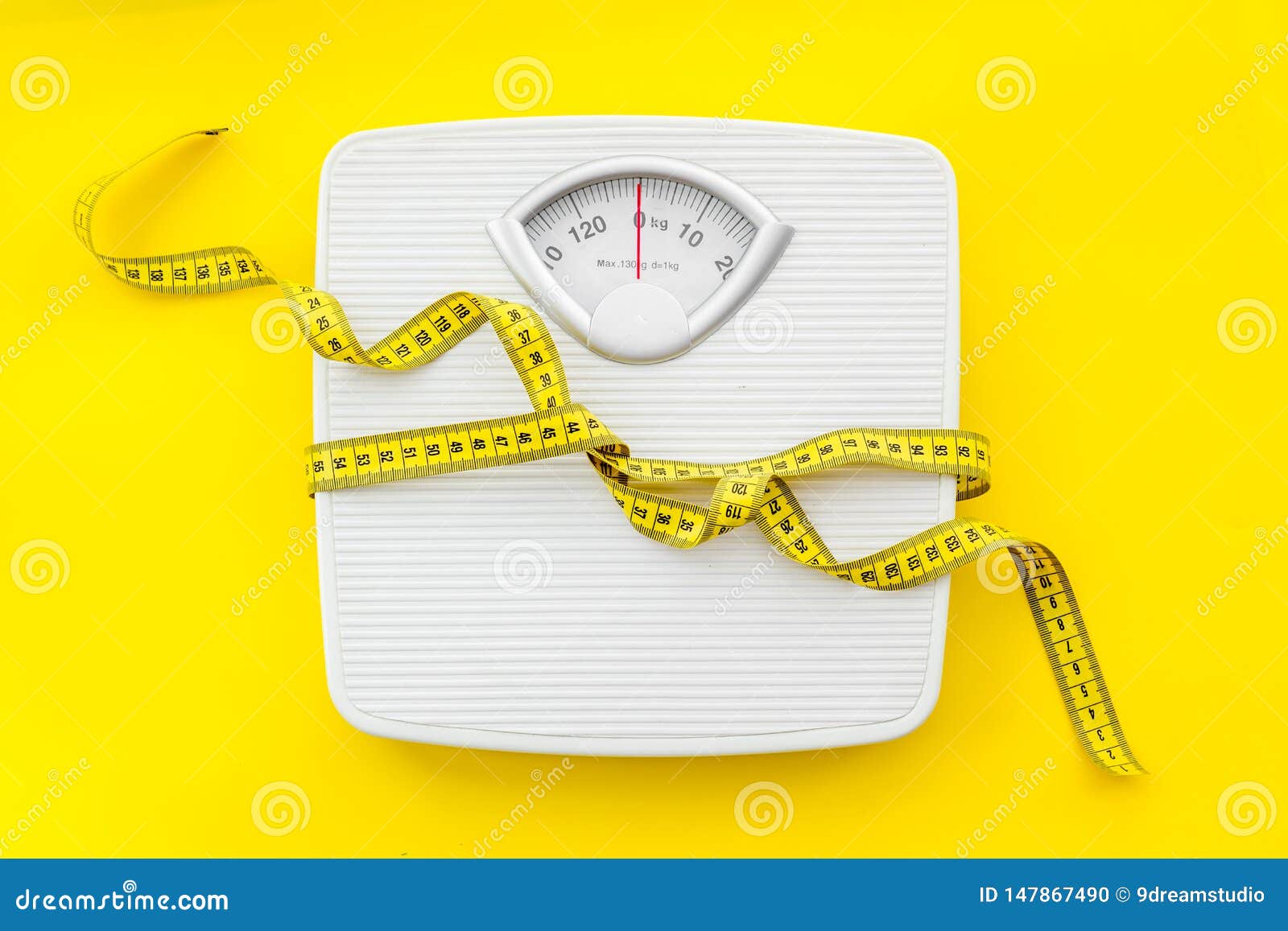 bathroom scales and measuring tape for weight loss concept on yellow  background top view Stock Photo
