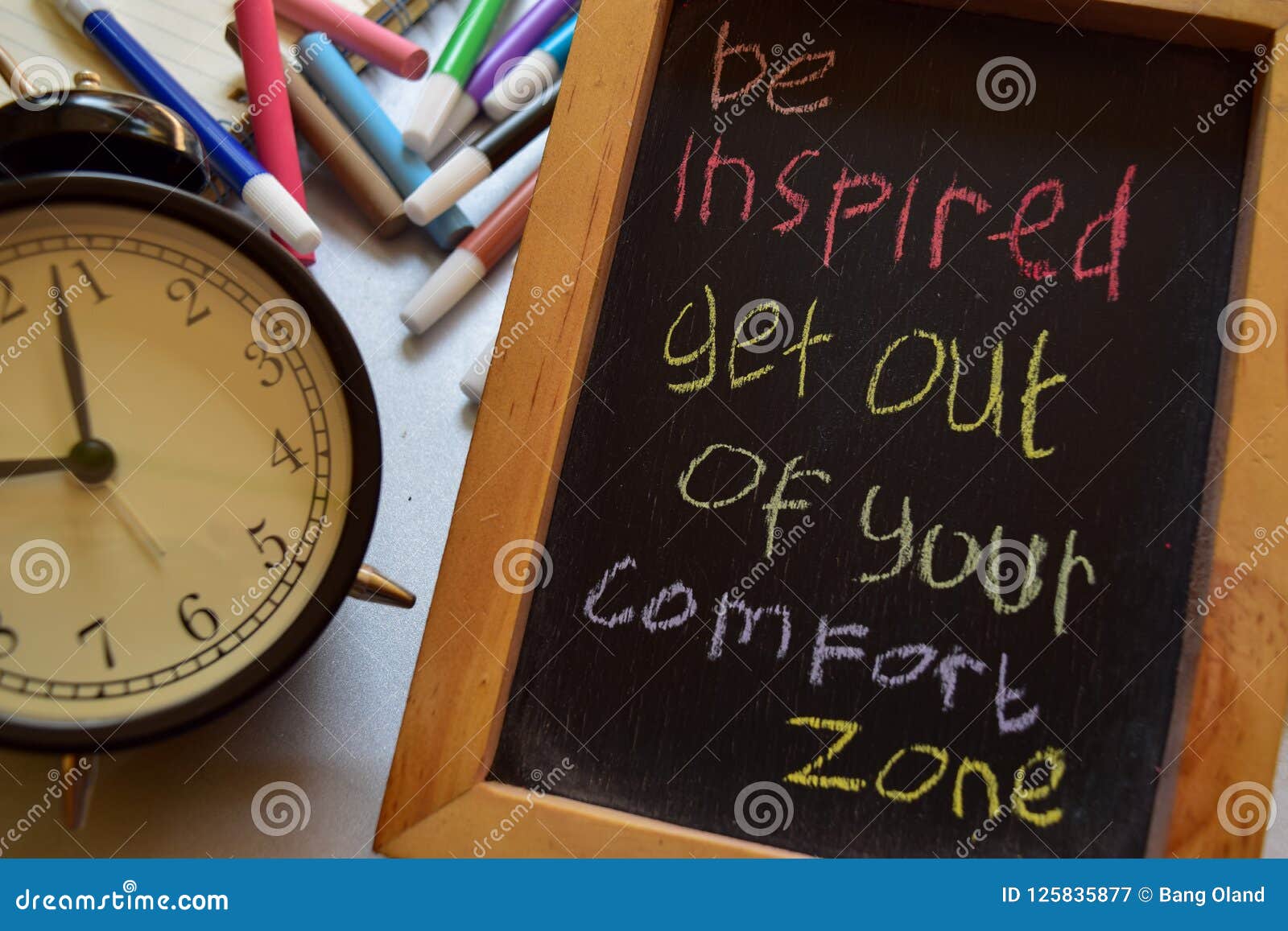 be inspired get out of your comfort zone on phrase colorful handwritten on chalkboard, alarm clock