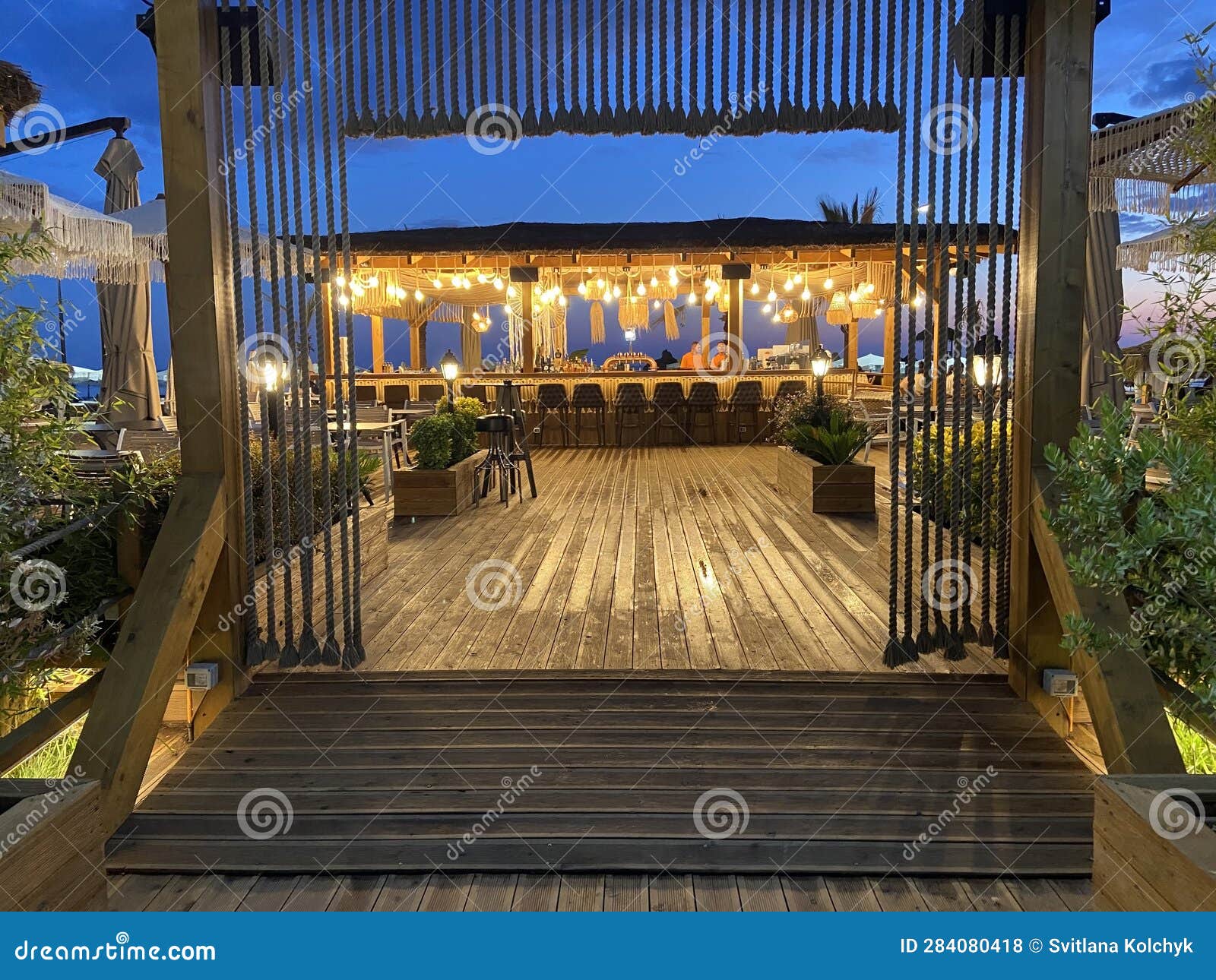 Beach Bar Counter with Chairs in Comfortable Restaurant at Night, View from the Entrance Stock