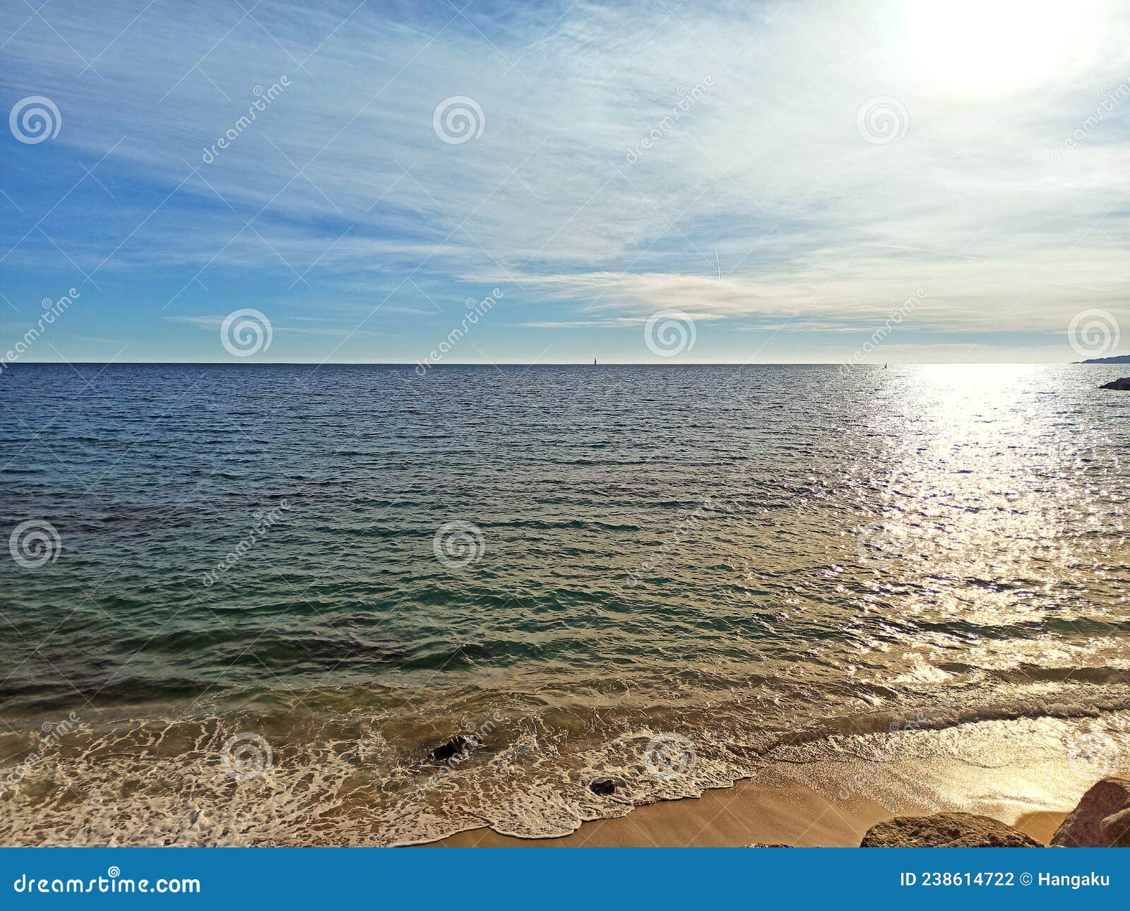 beach with calm dark blue sea and clear horizon with soft clouds.