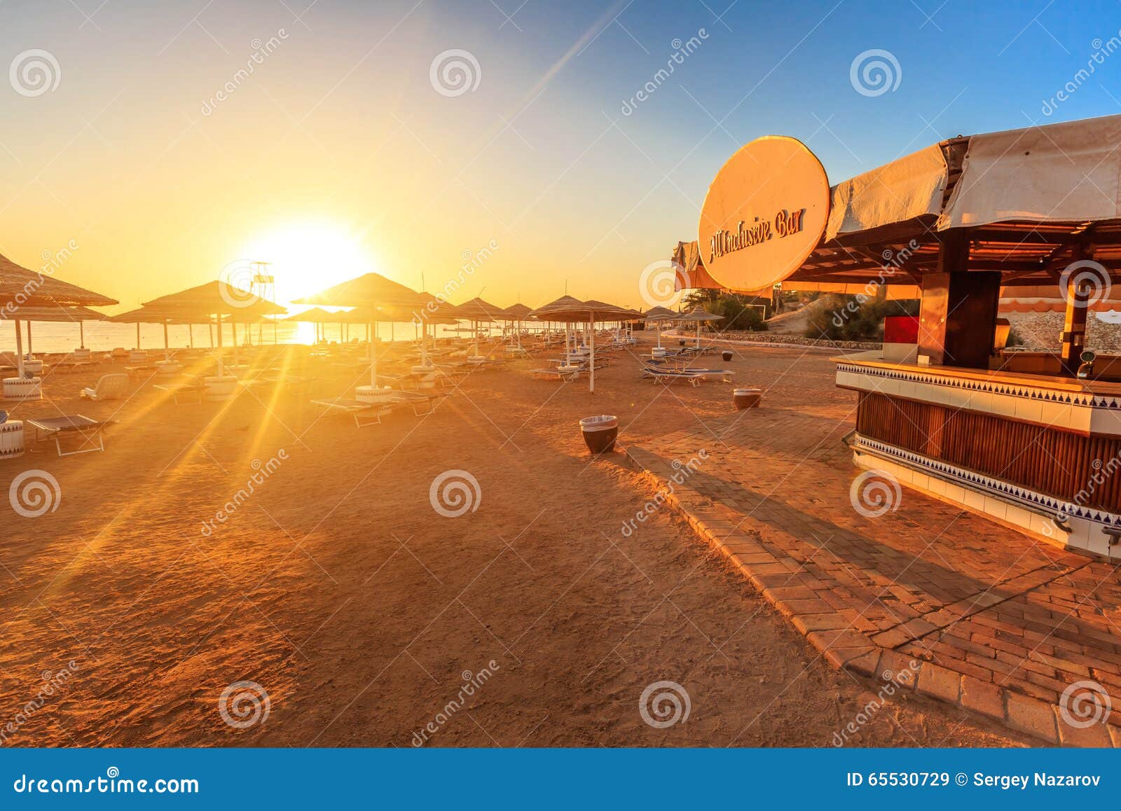 Beach with Deck Chairs, Parasol, and Bar during Sunrise Stock Image