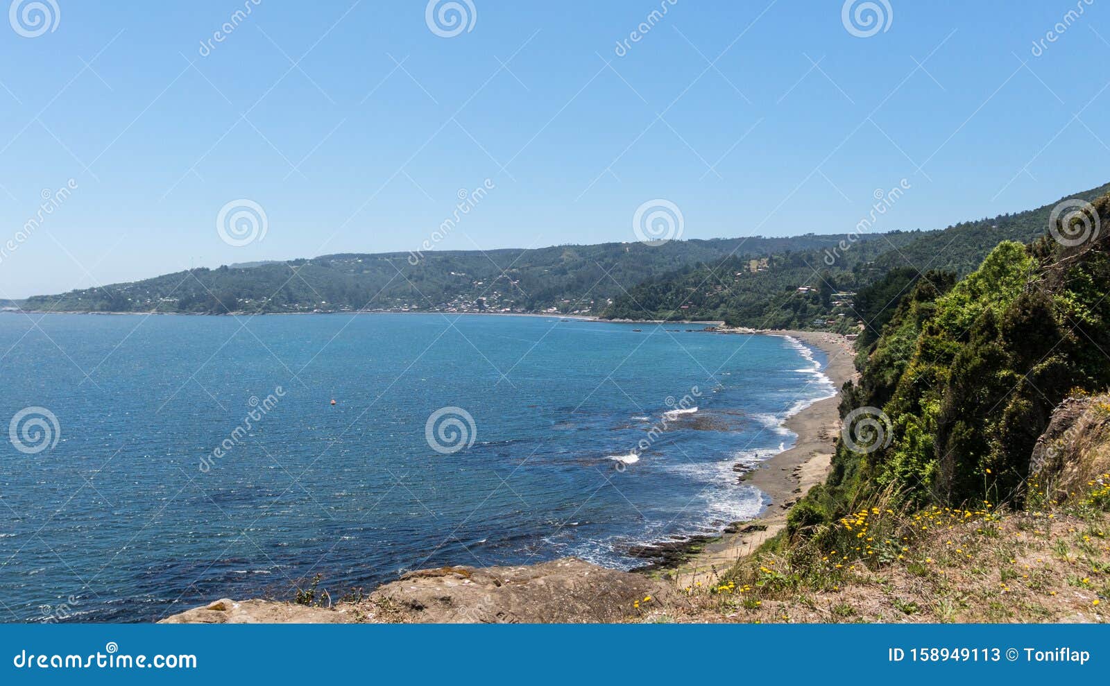 beach lovers facing the pacific ocean from the fort of niebla village. estuary and mouth of the valdivia river. valdivia, los rios