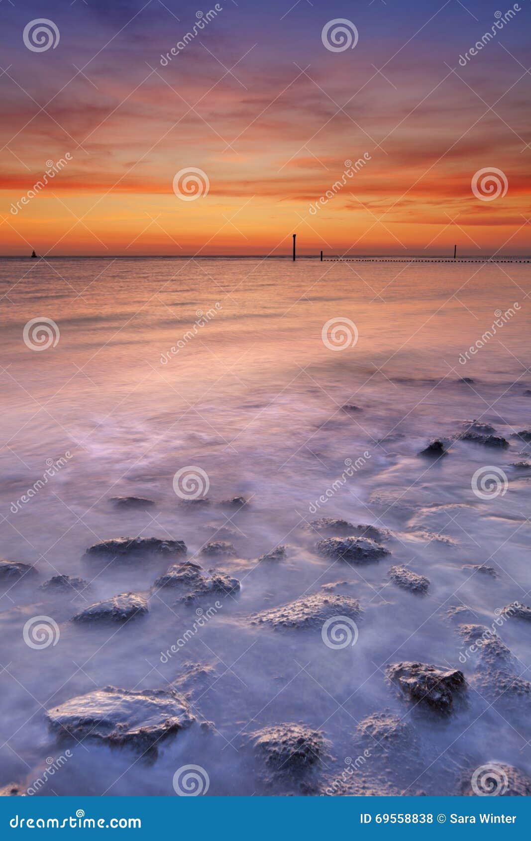 beach with rocks at sunset in zeeland, the netherlands