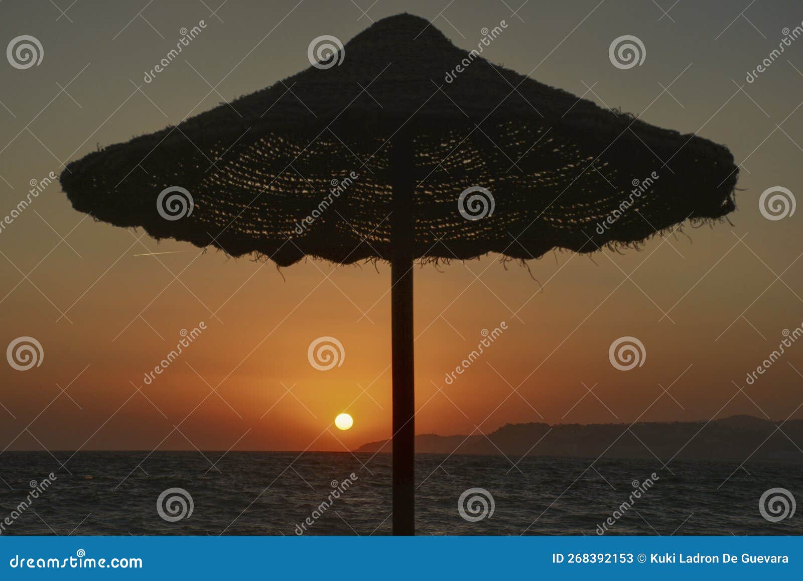 beach umbrella at sunset with setting sun