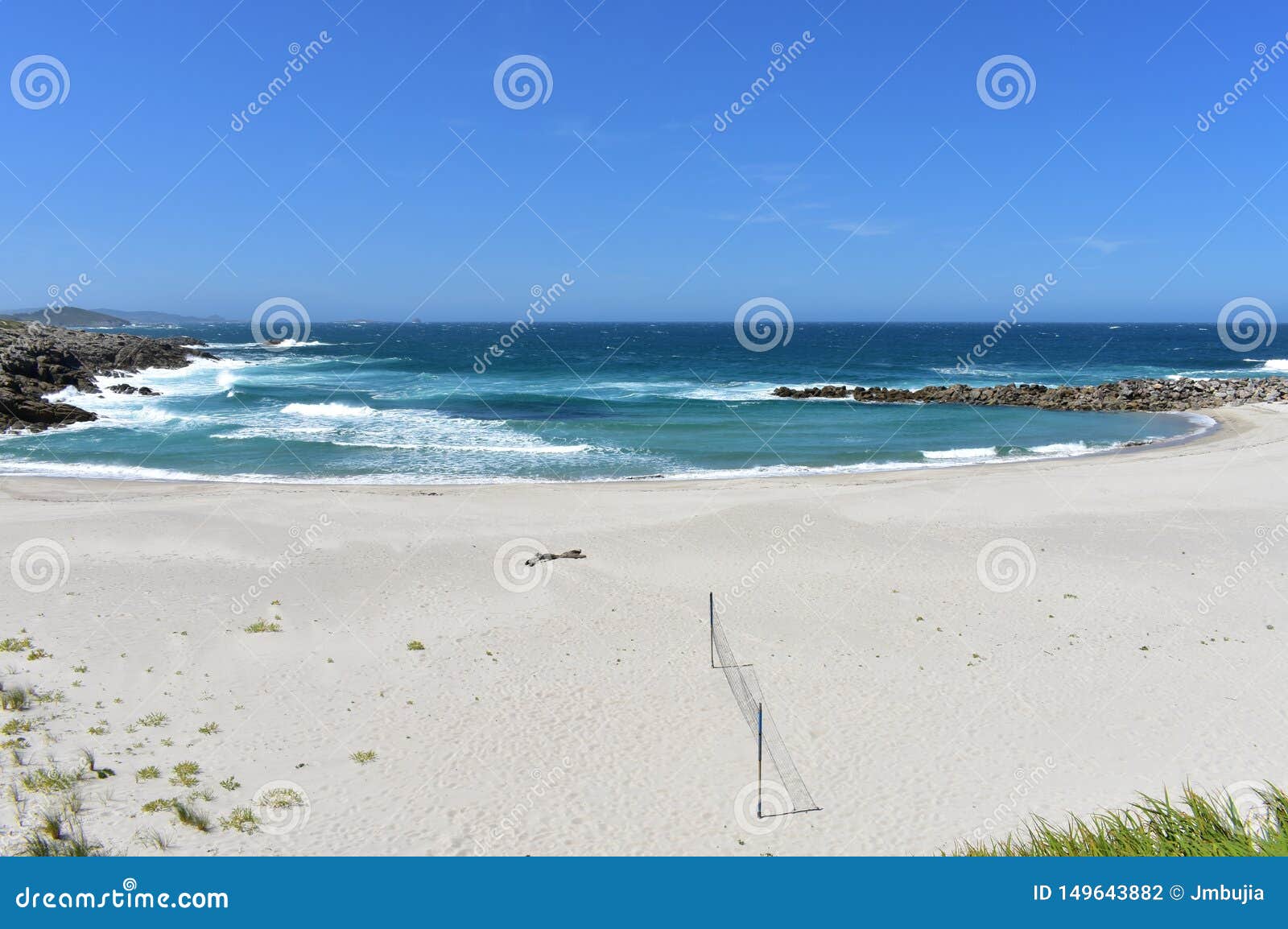beach with white sand, rocks and volleyball net. lugo, spain.