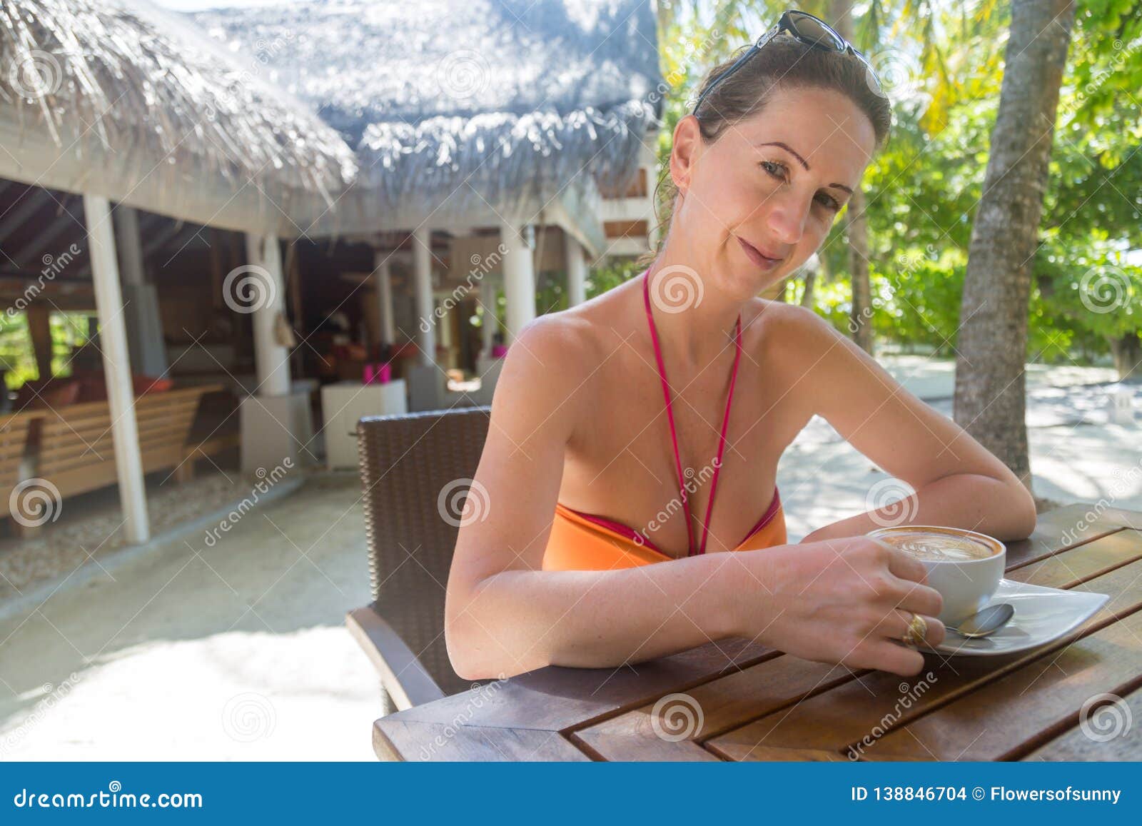Smiling woman with coffee cup sitting on jetty stock photo