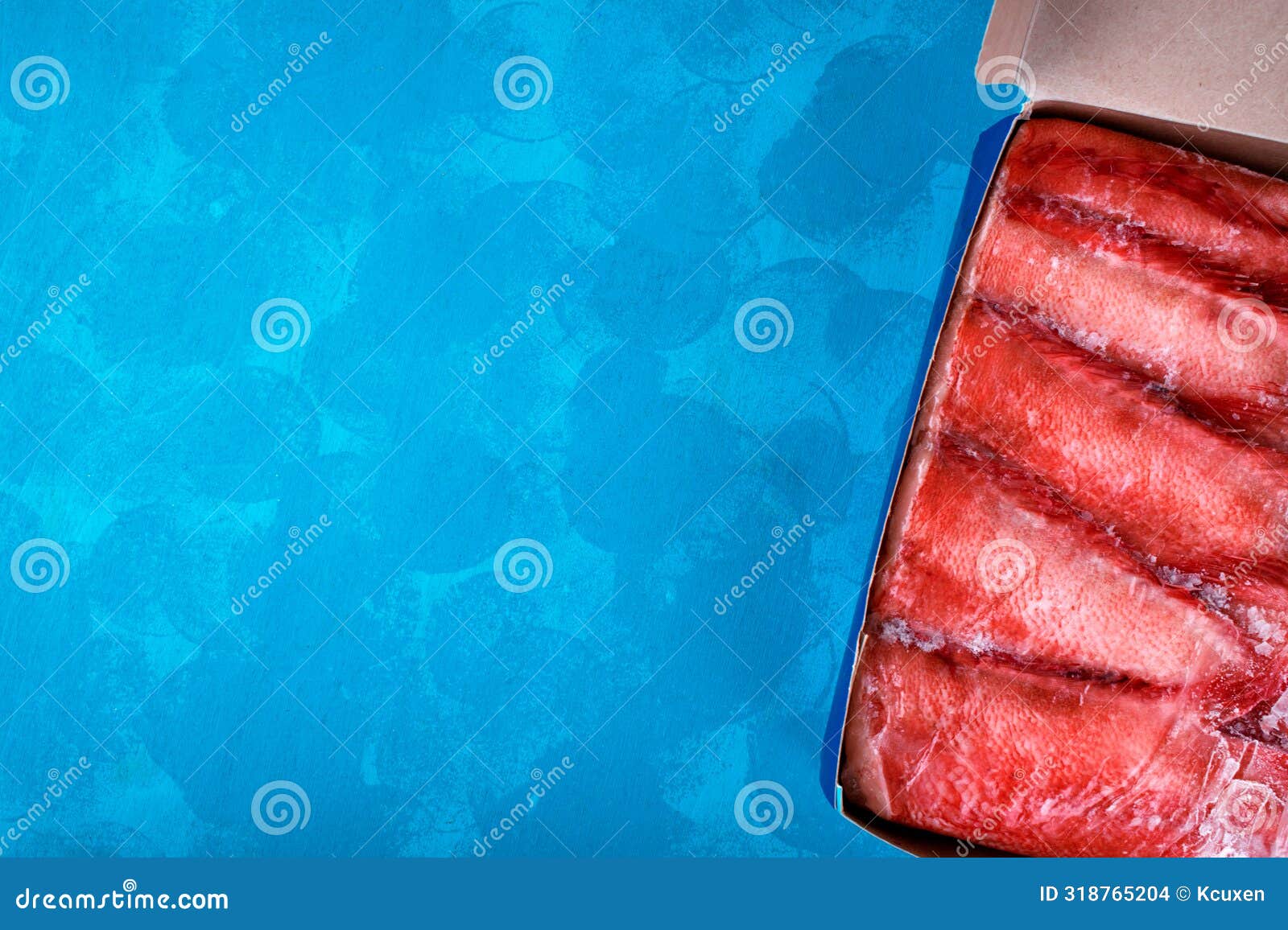 beaked redfish or sebastes mentella frozen in a row in a box on blue background.