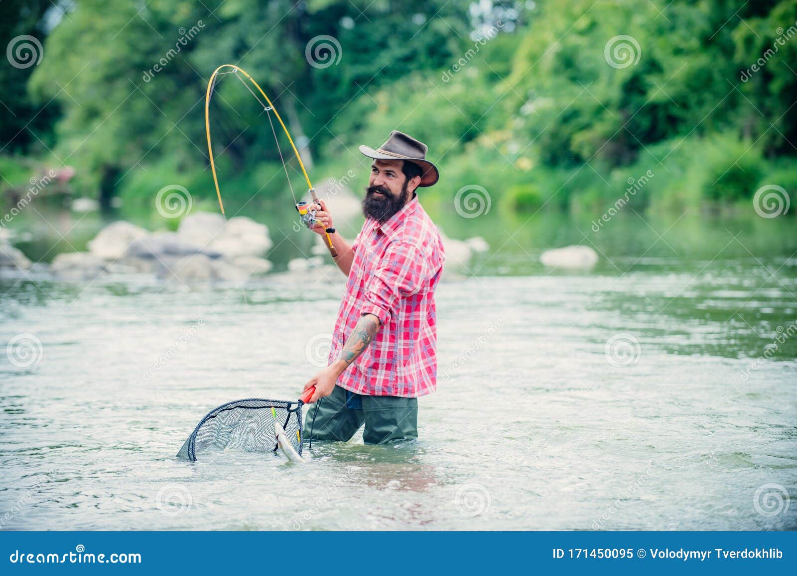 Bearded Fisher in Water. Young Man Fishing. Successful Fly Fishing