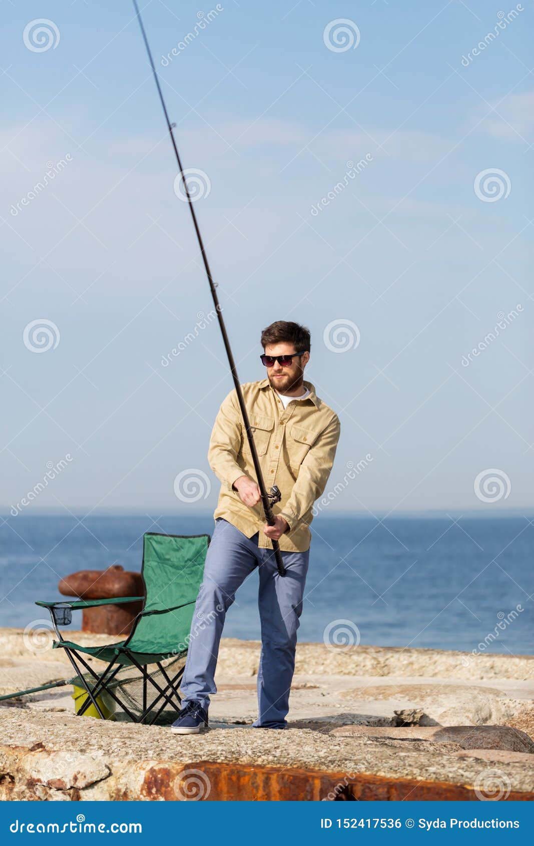 bearded fisherman with fishing rod on sea pier