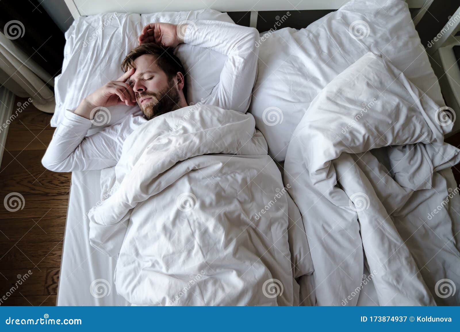 bearded man sleeps restlessly in bed, he is alarmed and had a terrible nightmare.