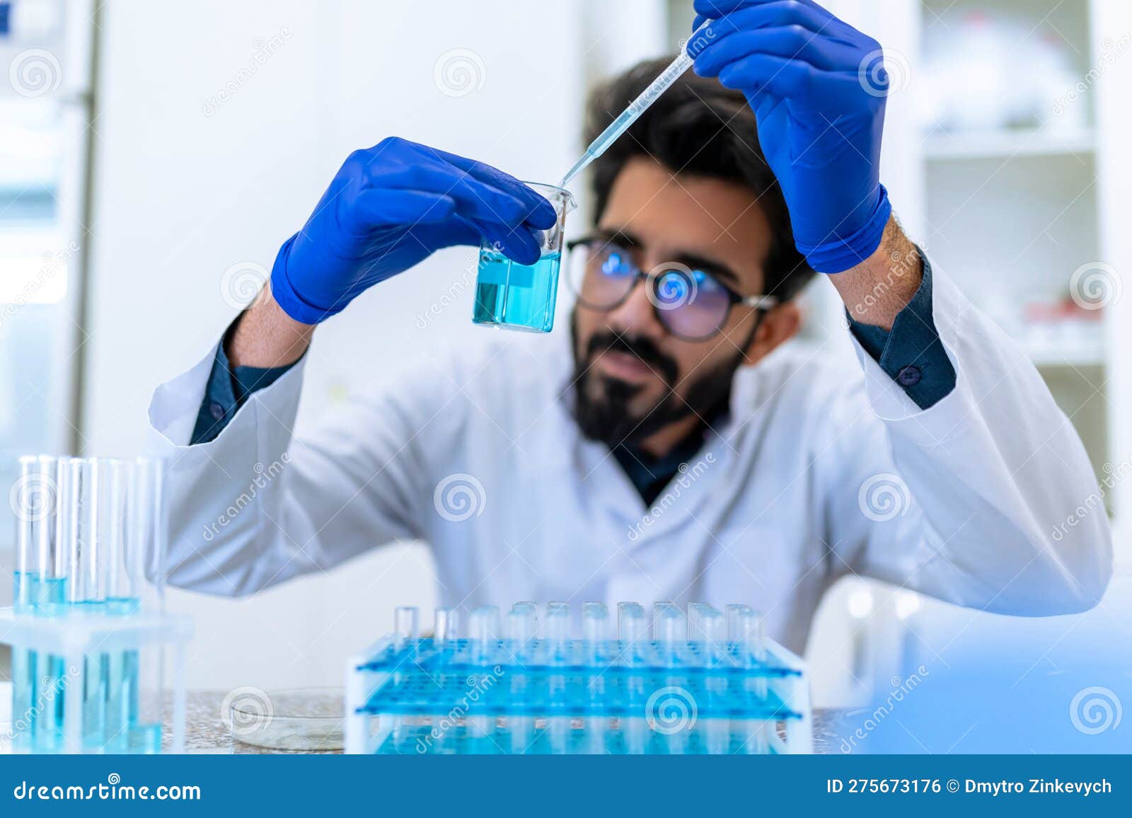 scientist man testing chemical sample in flask at laboratory with lab glassware.