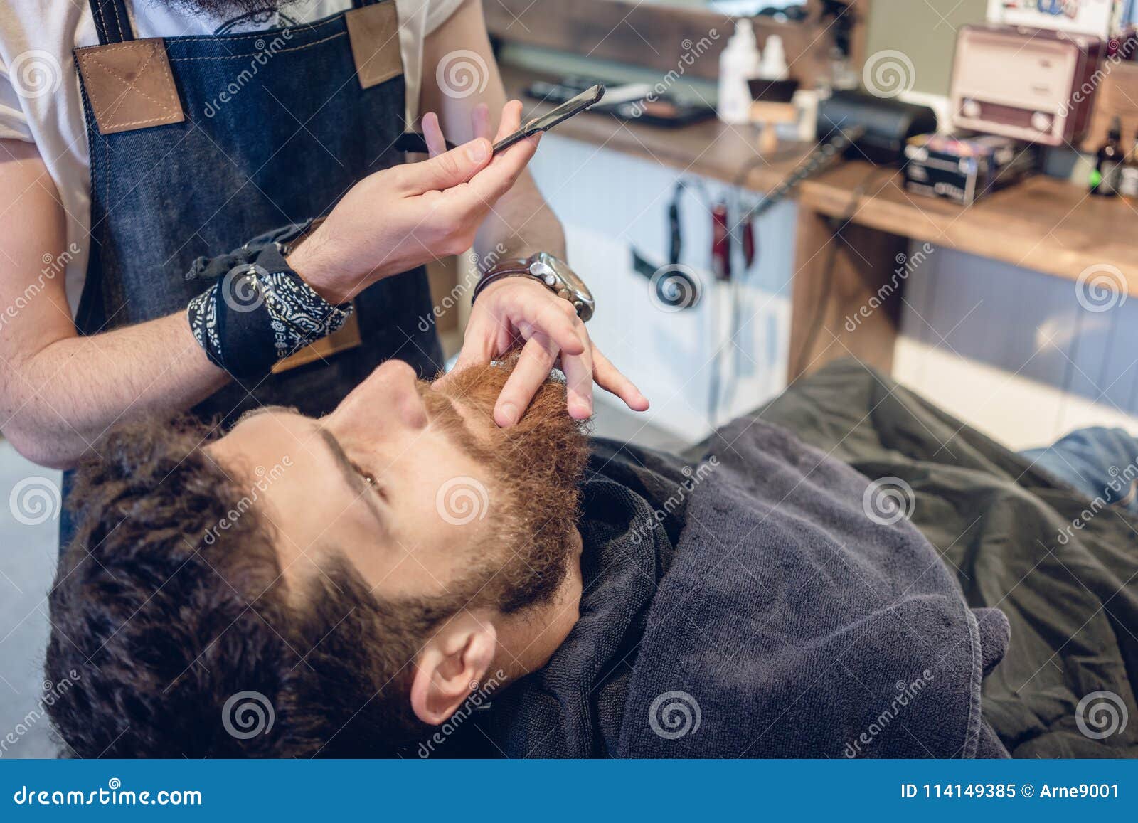 bearded young man ready for shaving in the hair salon of a skilled barber