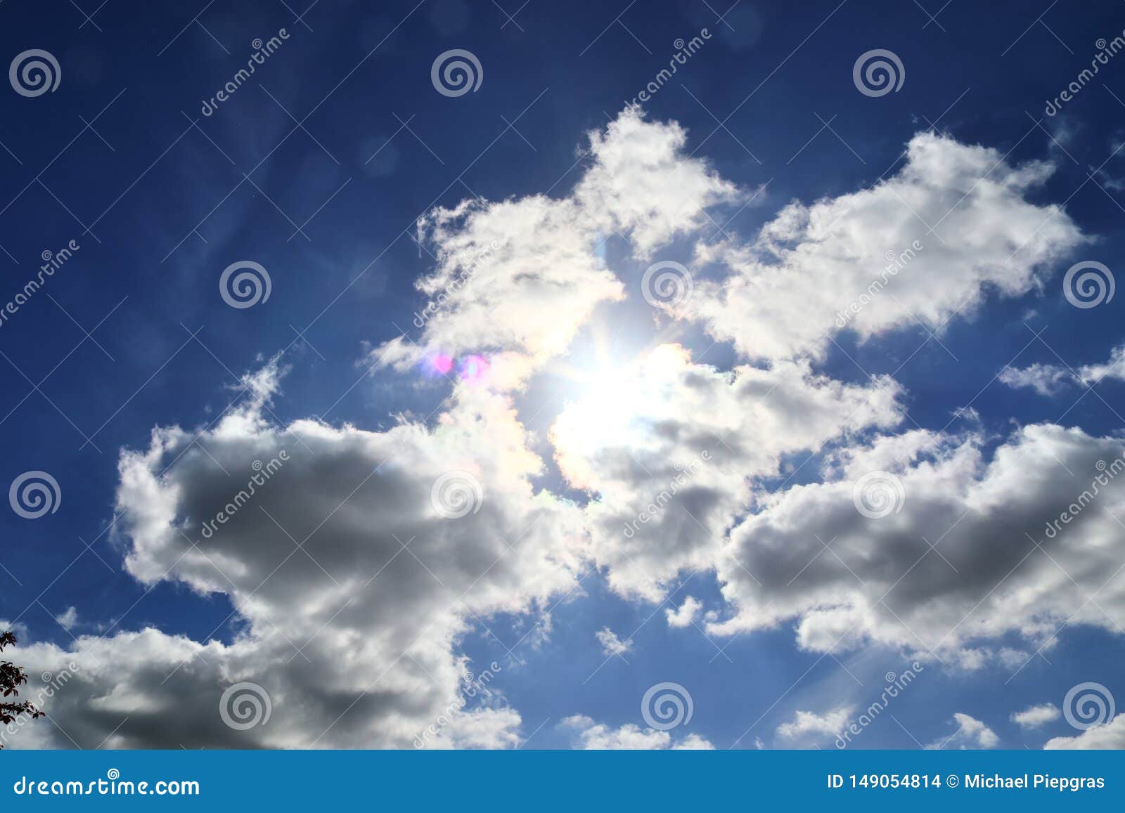 beaufitul shots of the sun with light beams and flares on a blue sky with some clouds