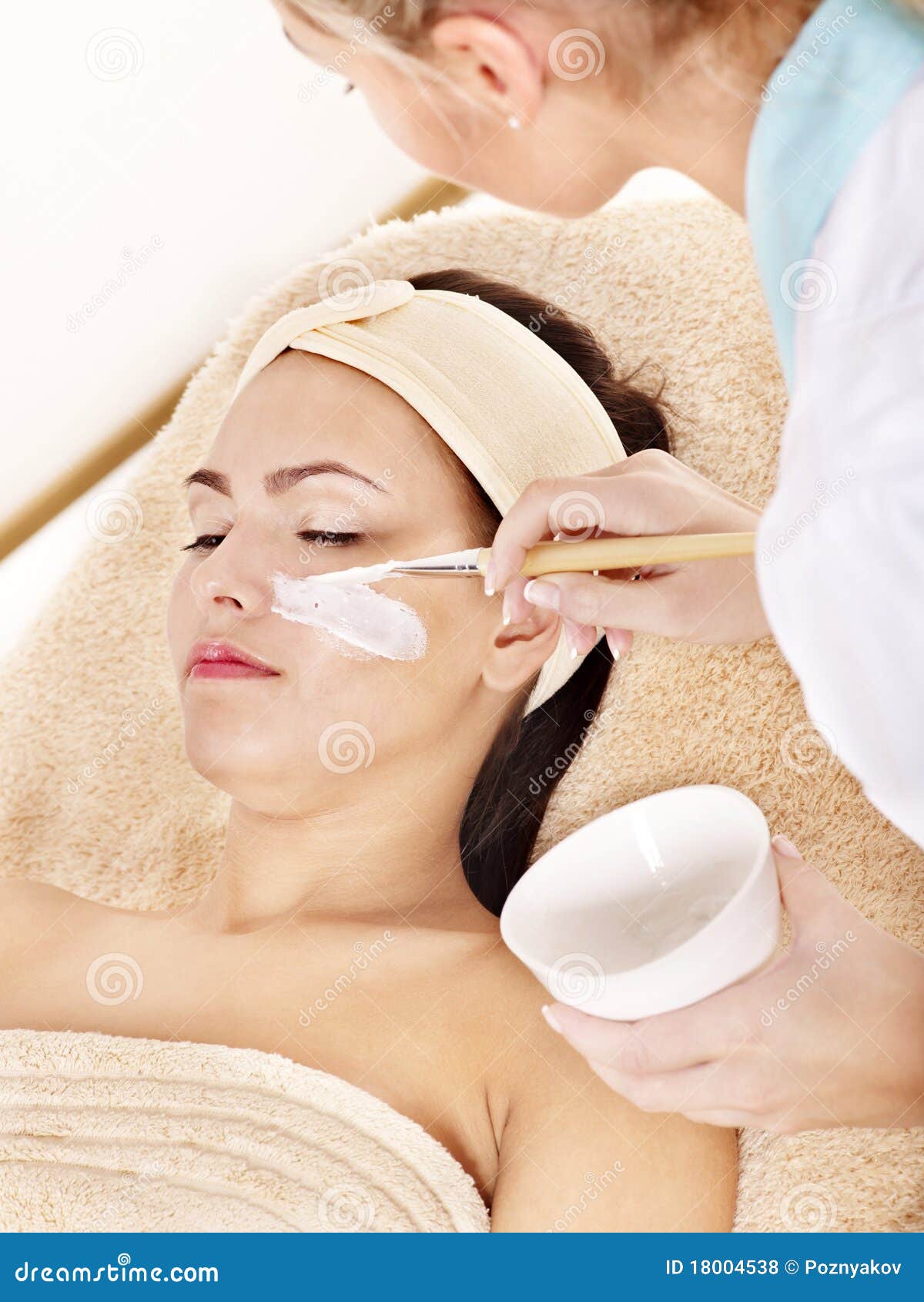 beautician applying facial mask by woman.