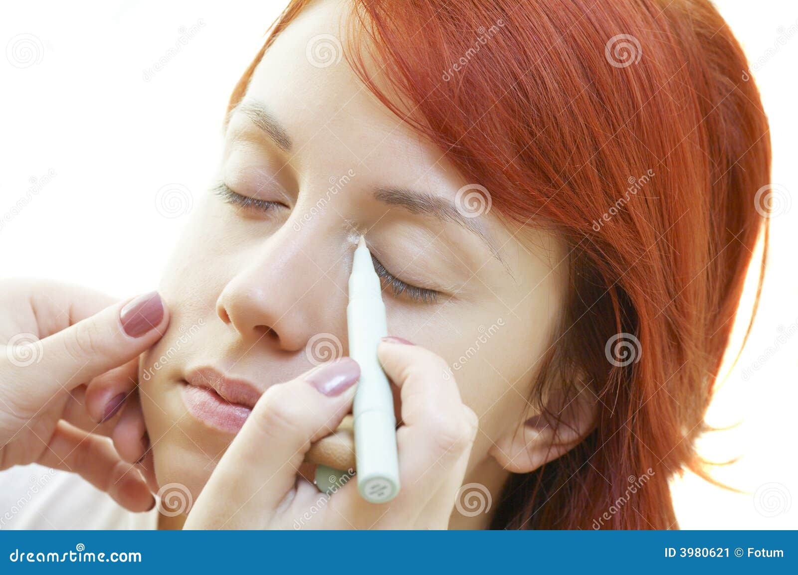beautician is doing make-up to red-haired girl