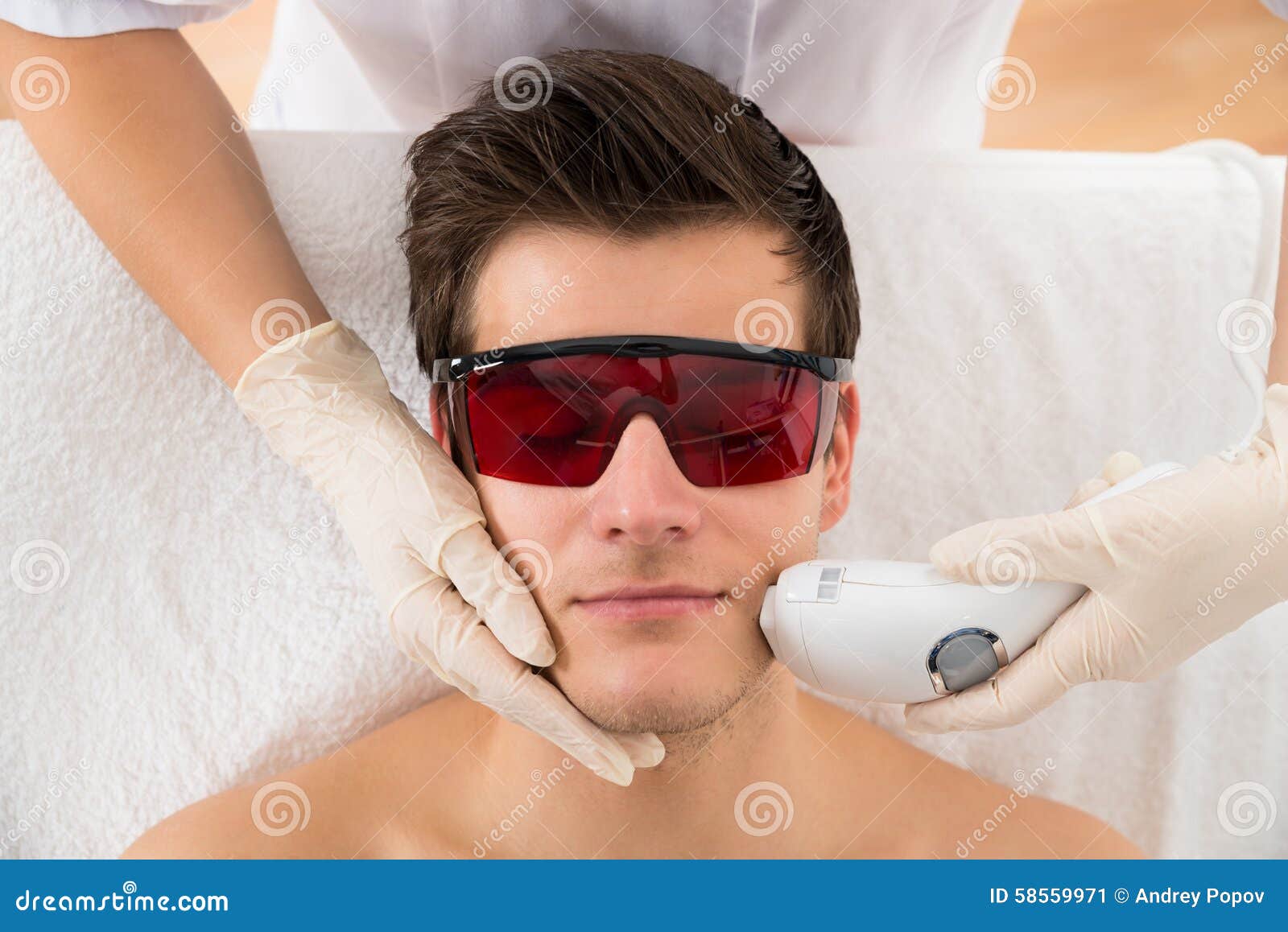 beautician giving laser epilation treatment to man face