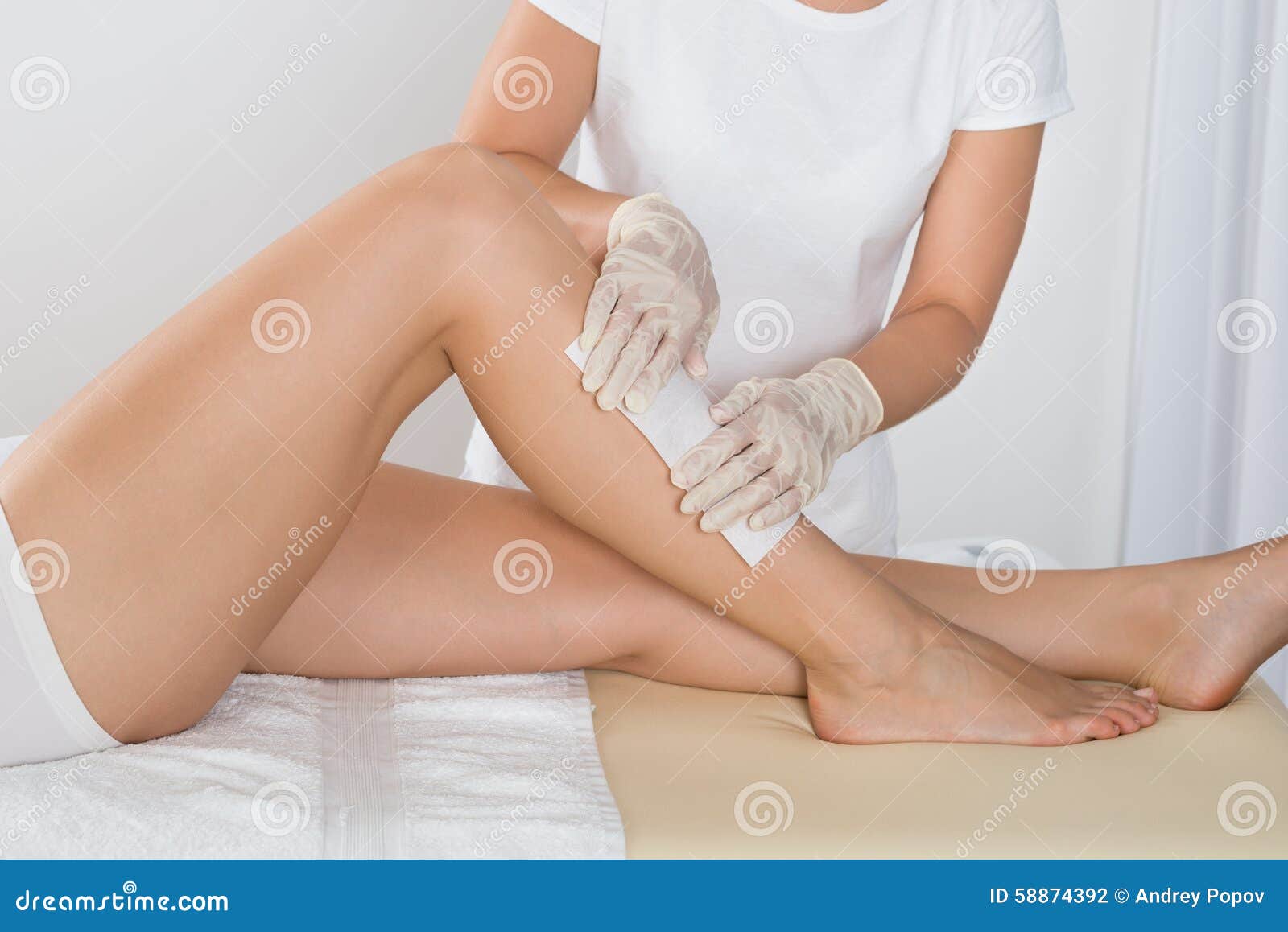 beautician waxing leg of woman