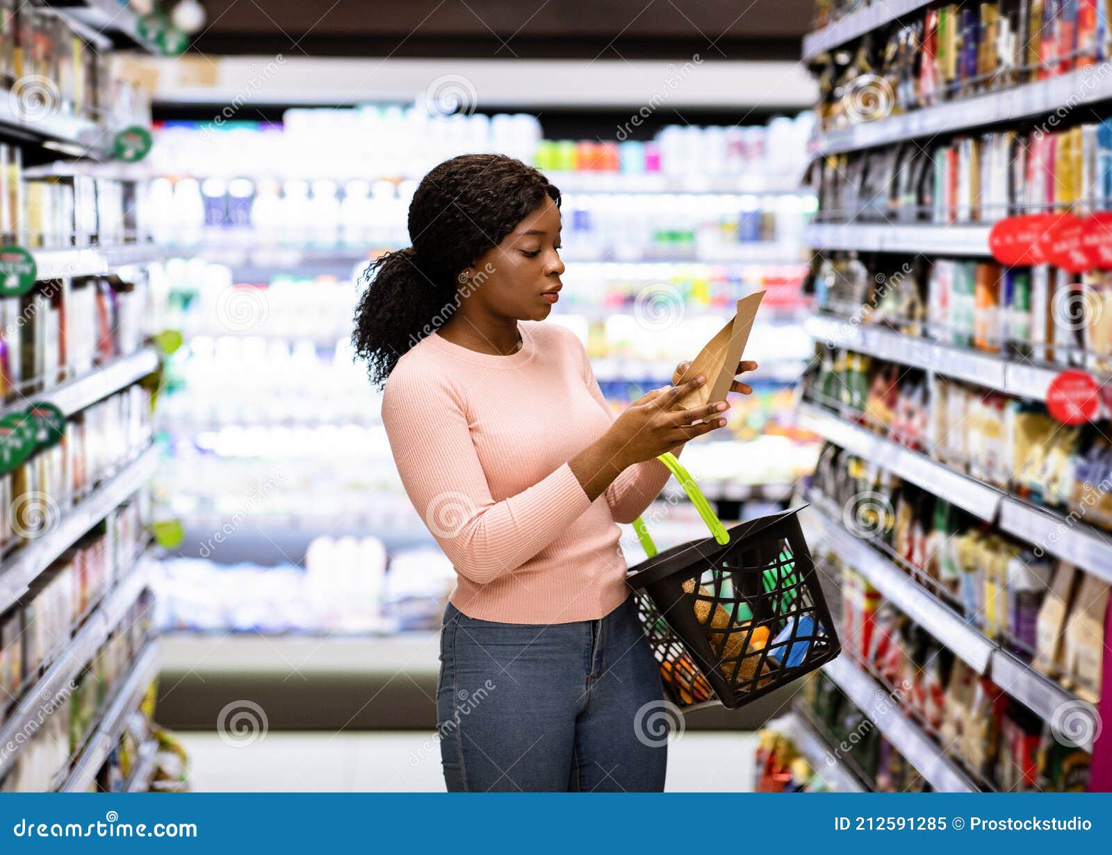 beautiful african american woman making choice of products at supermarket