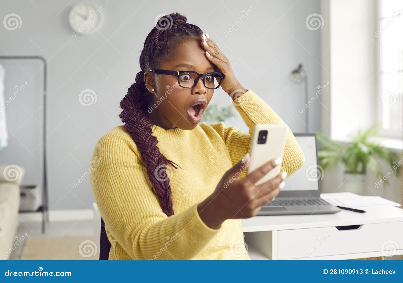 beautiful africanamerican woman looks at the phone in horror.