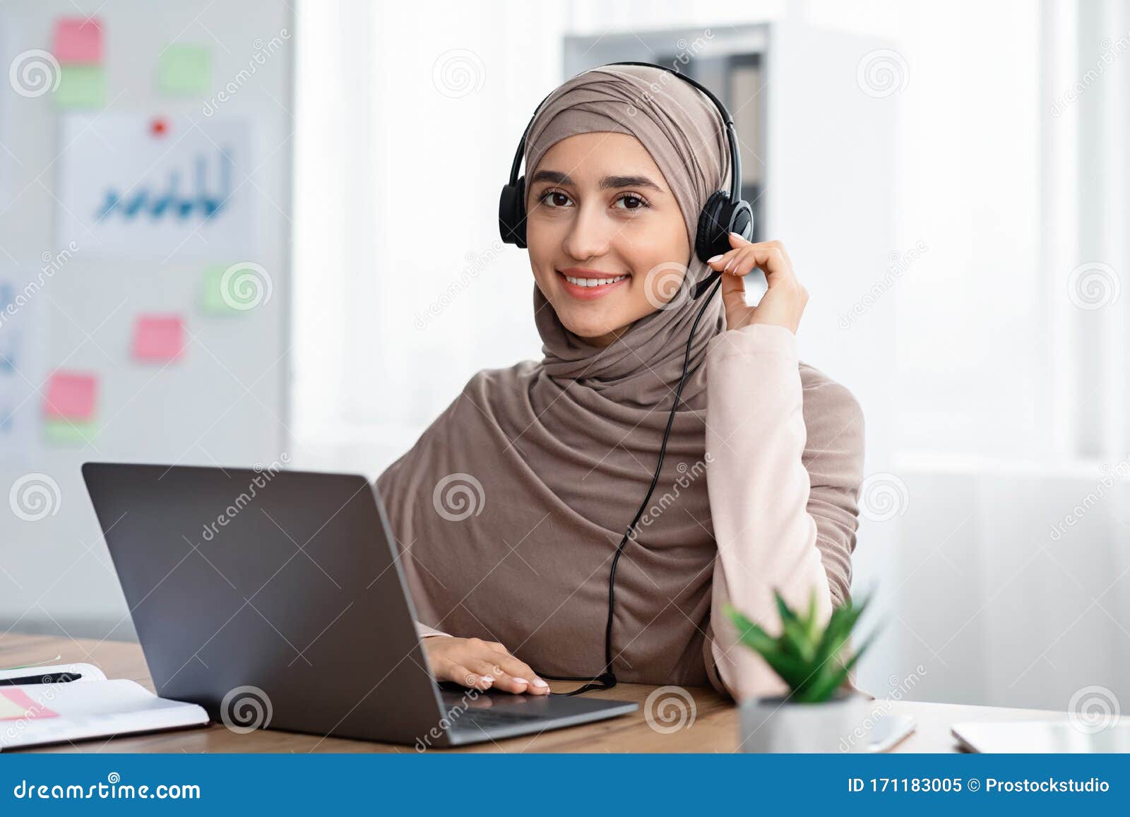 Beautiful Arabic Woman In Hijab Wearing Headset Working In Modern