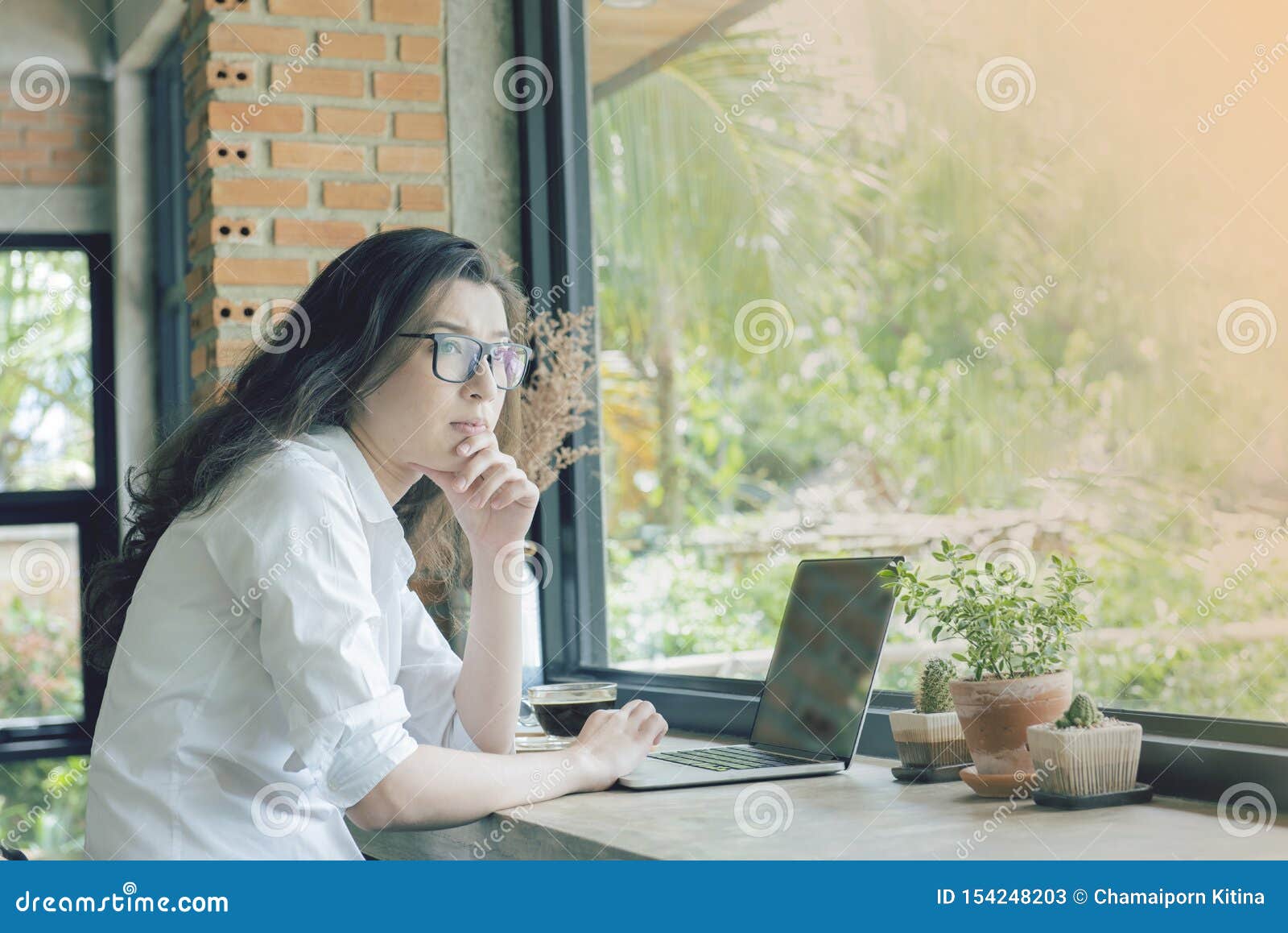 beautiful asian woman.sit in cafe shop look out side window with serious face. e-commerce, university education, internet