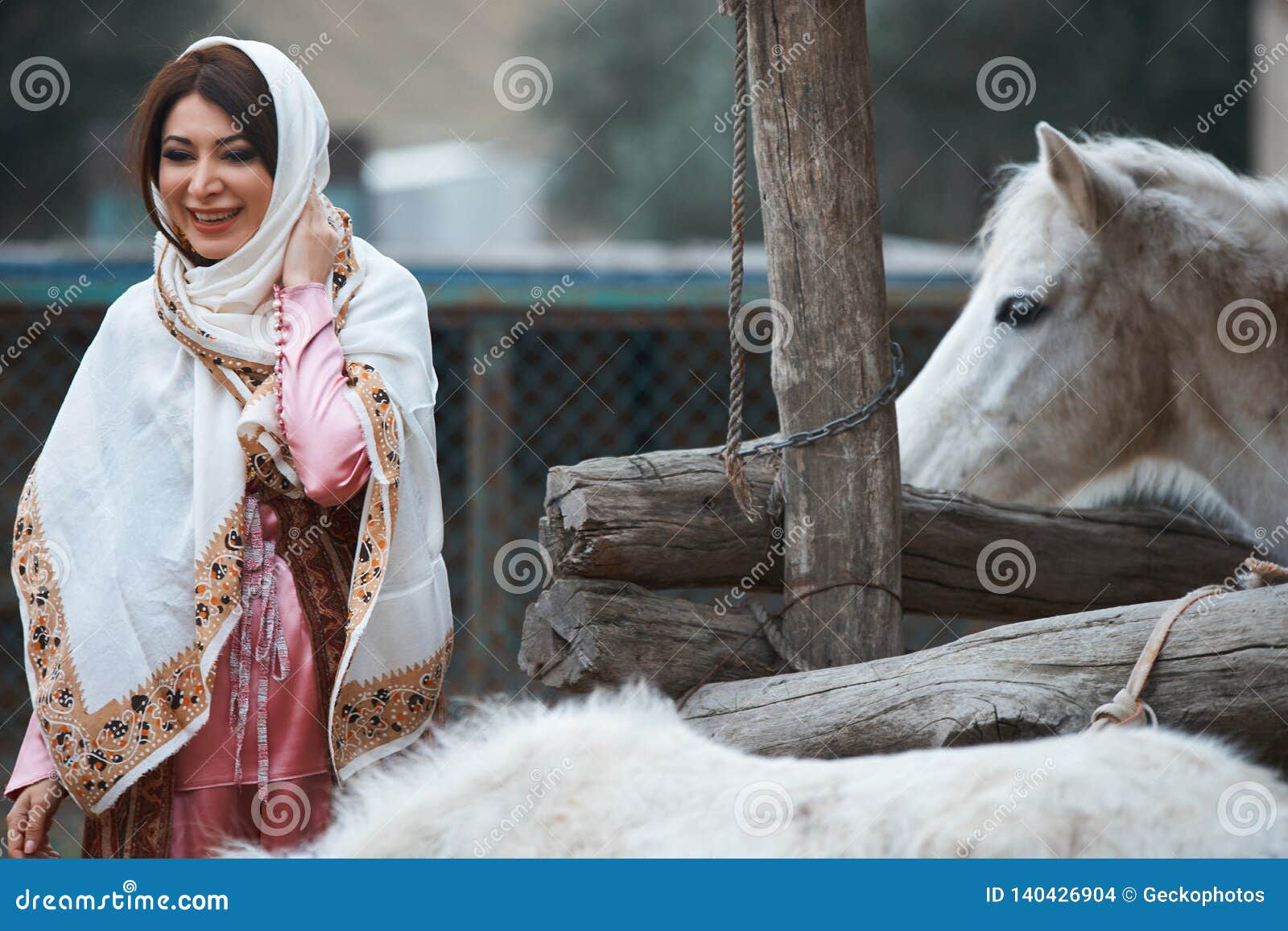 beautiful azeri woman in traditional azerbaijani dress standing with white horse