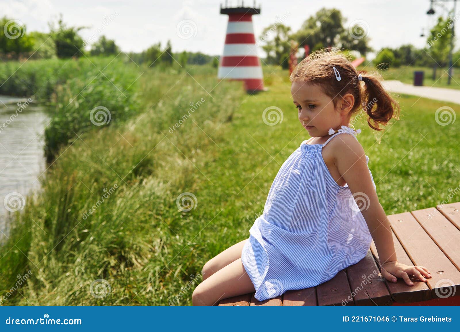 Beautiful Baby Girl Sitting on a Wooden Bench on a River Bank and ...