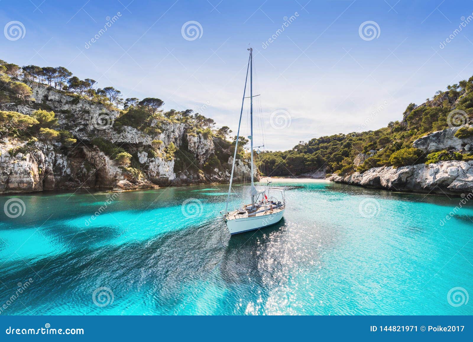 beautiful beach with sailing boat yacht, cala macarelleta, menorca island, spain. yachting, travel and active lifestyle concept