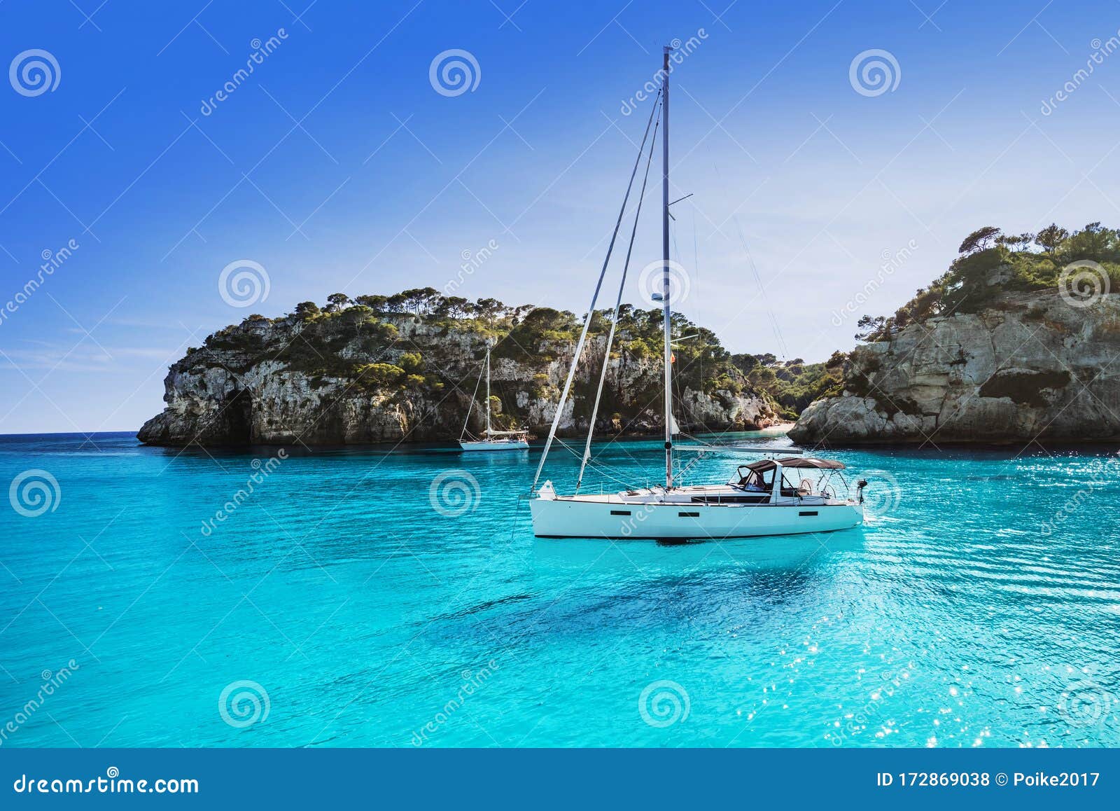 beautiful beach with sailing boat yacht, cala macarelleta, menorca island, spain. yachting, travel and active lifestyle concept