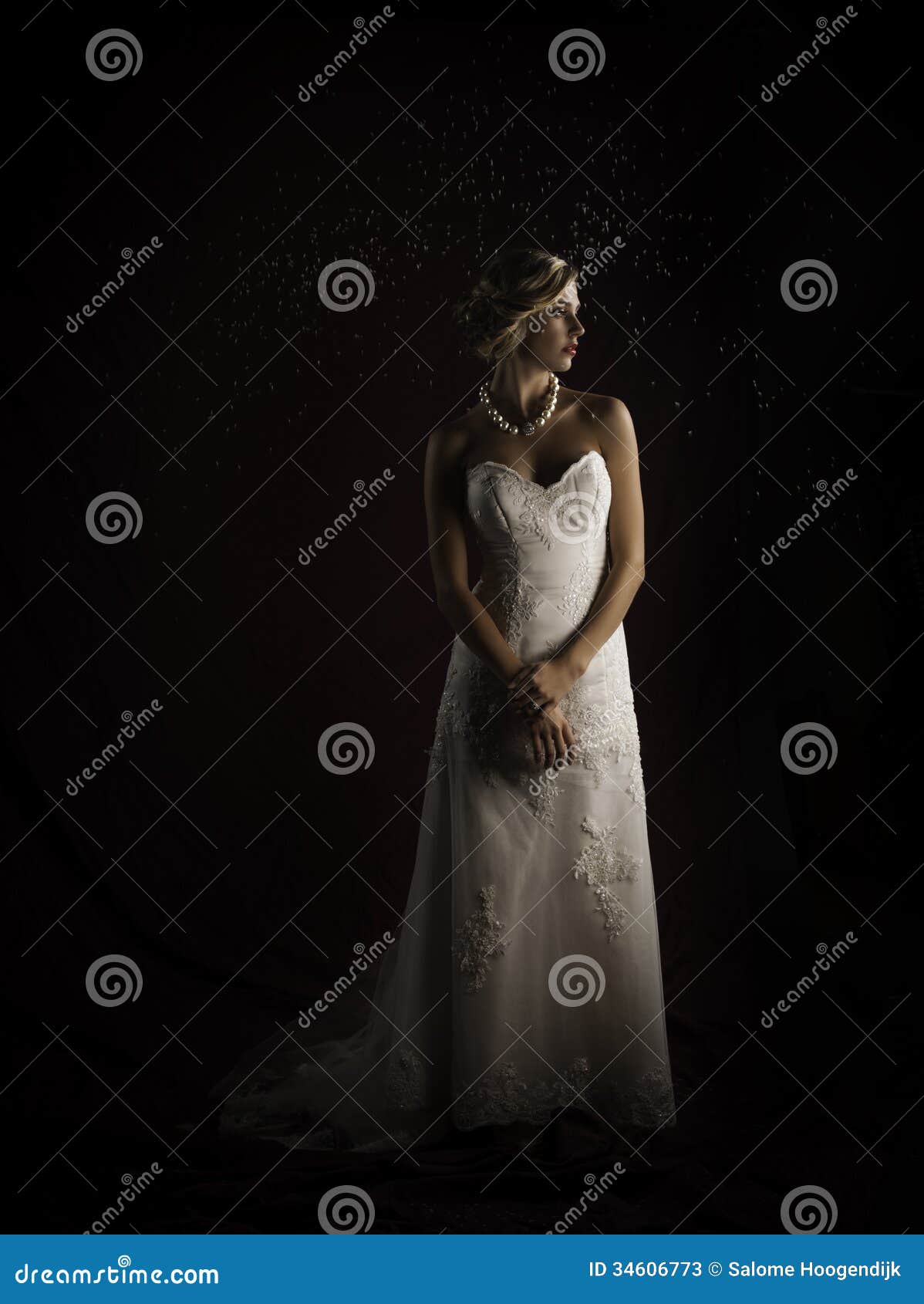 beautiful blonde bride wearing vintage strapless wedding gown standing in the rain