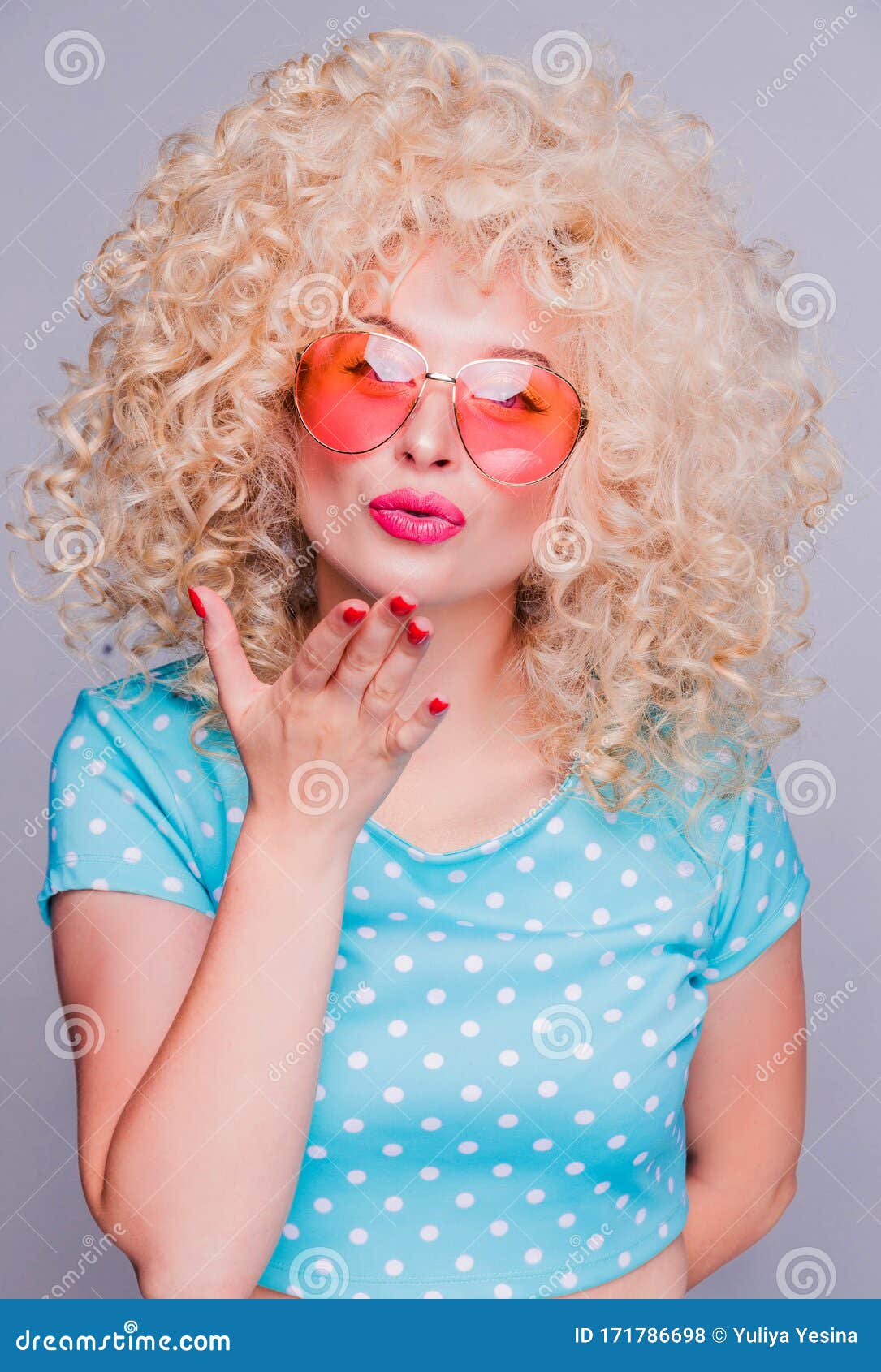 Beautiful Blonde Girl In Retro Style With A Voluminous Curly Hairstyle In A Blue Polka Dot