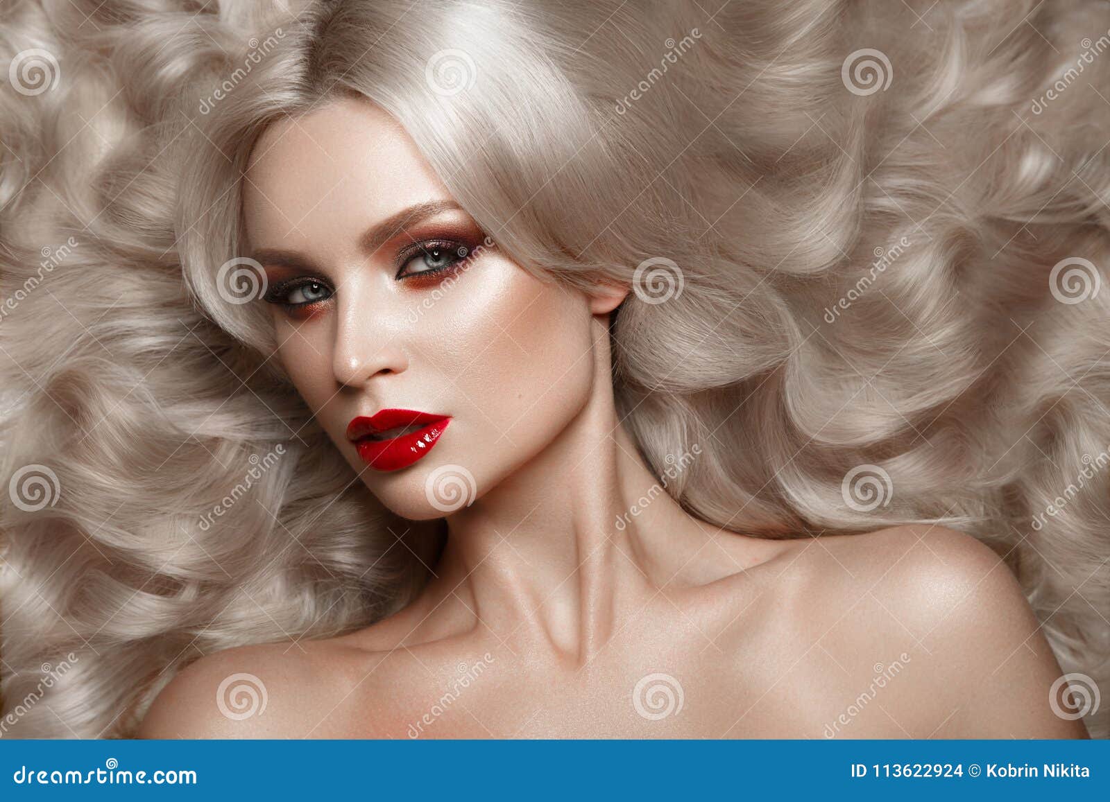 beautiful blonde in a hollywood manner with curls, natural makeup and red lips. beauty face and hair.