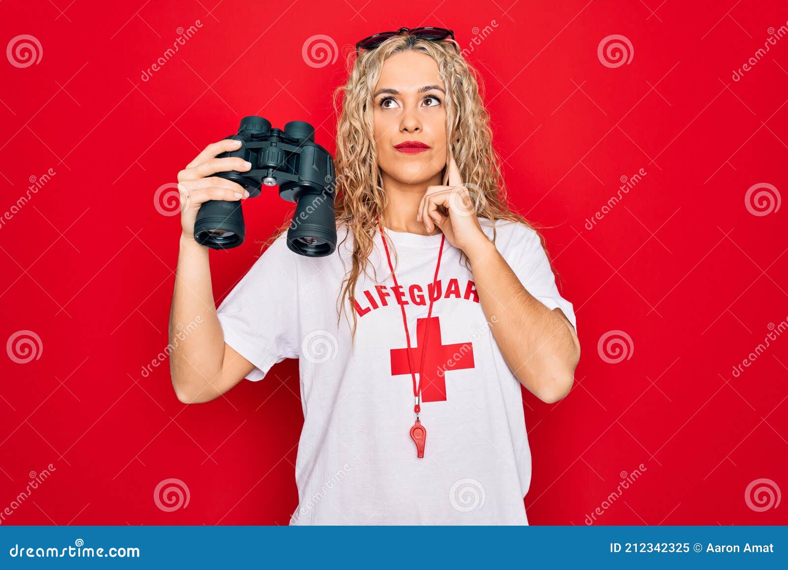 Beautiful Blonde Lifeguard Woman Wearing T Shirt With Red Cross And Whistle Using Binoculars