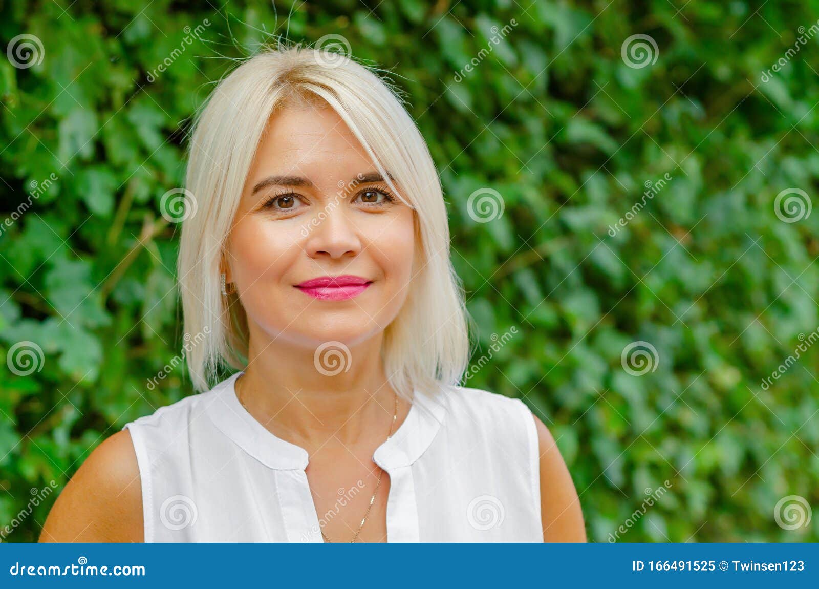 Beautiful Blonde Middle-aged Woman In Green Leaves 
