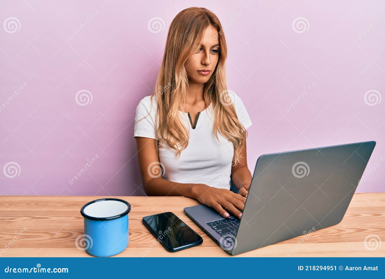 beautiful blonde young woman working using computer laptop thinking attitude and sober expression looking self confident