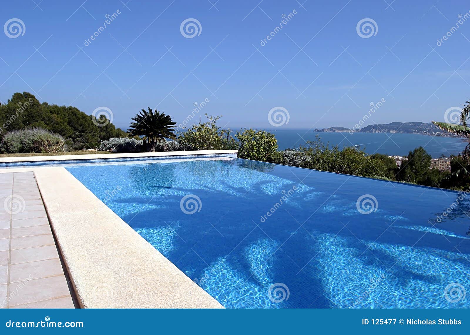 beautiful blue fresh infinity swimming pool in a villa in sunny spain with sea views