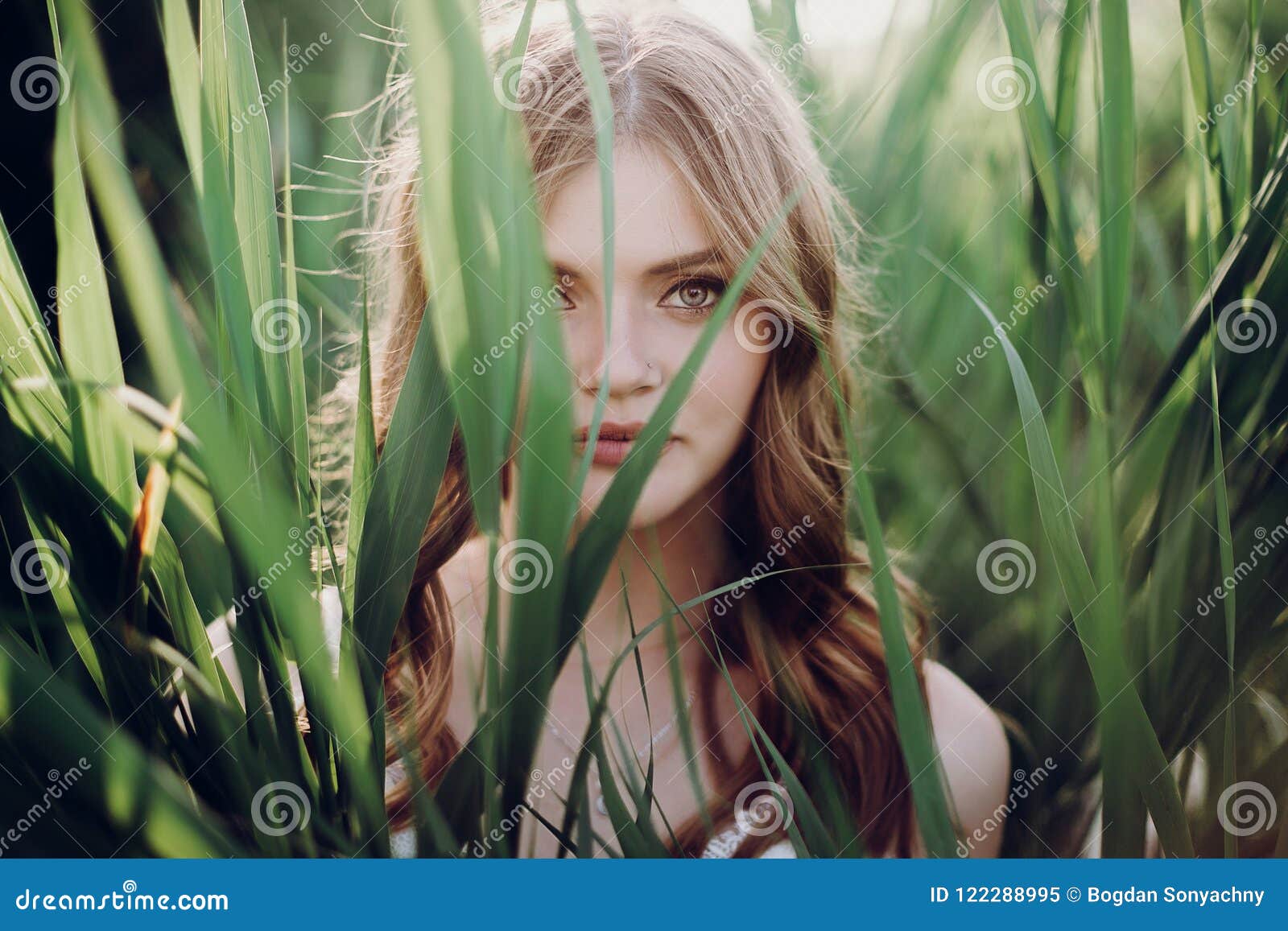 Beautiful Boho Girl Embracing in Grass at Sunset Light Near Lake Stock