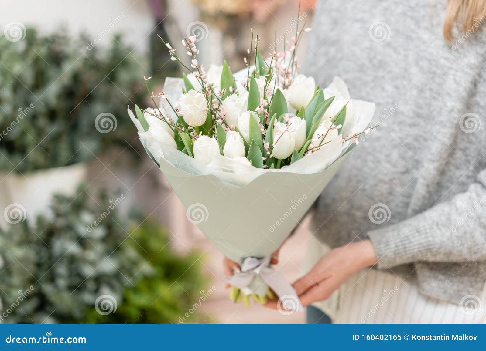 beautiful bouquet of white tulips flowers in woman hand. the work of the florist at a flower shop. cute lovely girl
