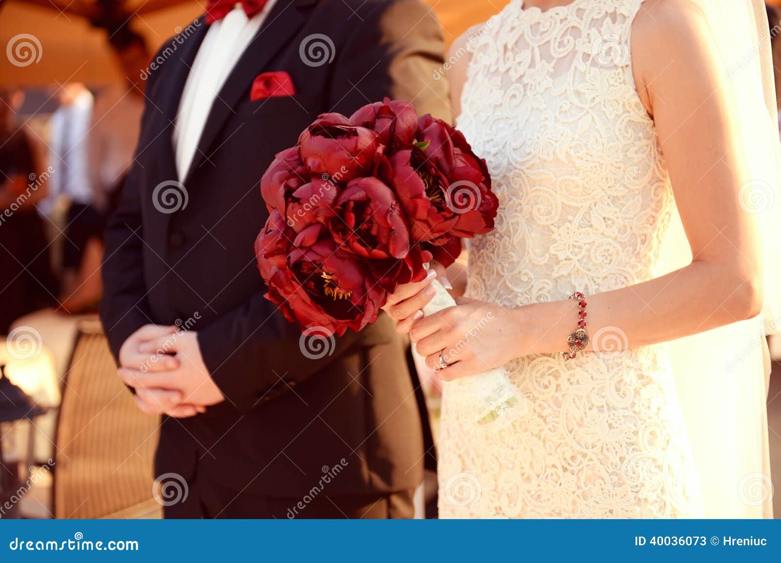 Beautiful bride and groom holding red flowers bouquet in hands
