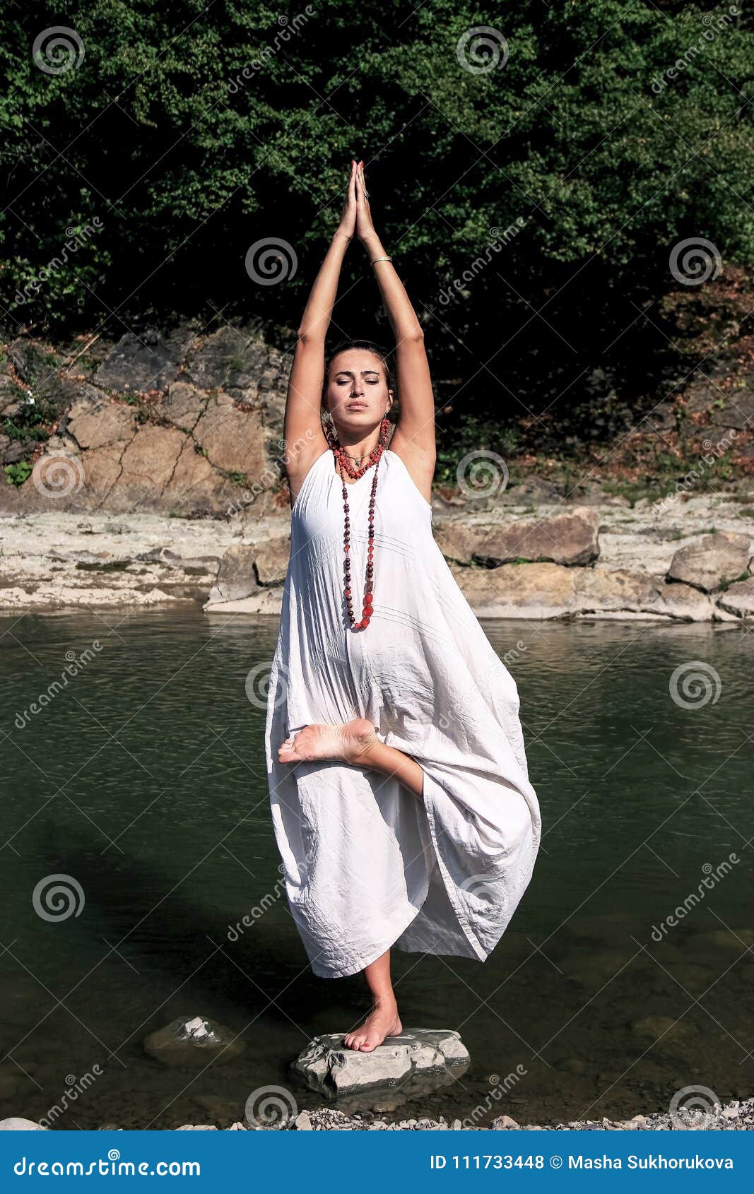 Girl In White Dress Is Engaged In Yoga, Beautiful Brunette In Long White  Dress, Young Woman Is Doing Yoga In The Mountains, Brunette Is Doing  Exercises From Yoga In Yoga On Background