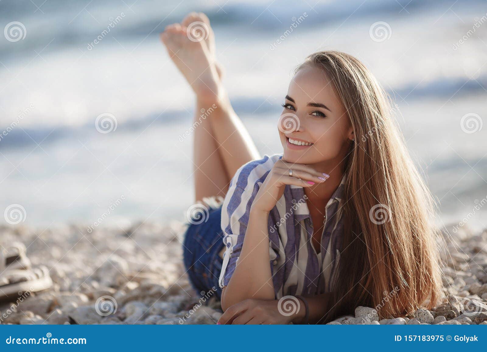 A Beautiful Young Woman With Long Straight Hair Sits Alone On Stones By The Sea Stock Image 
