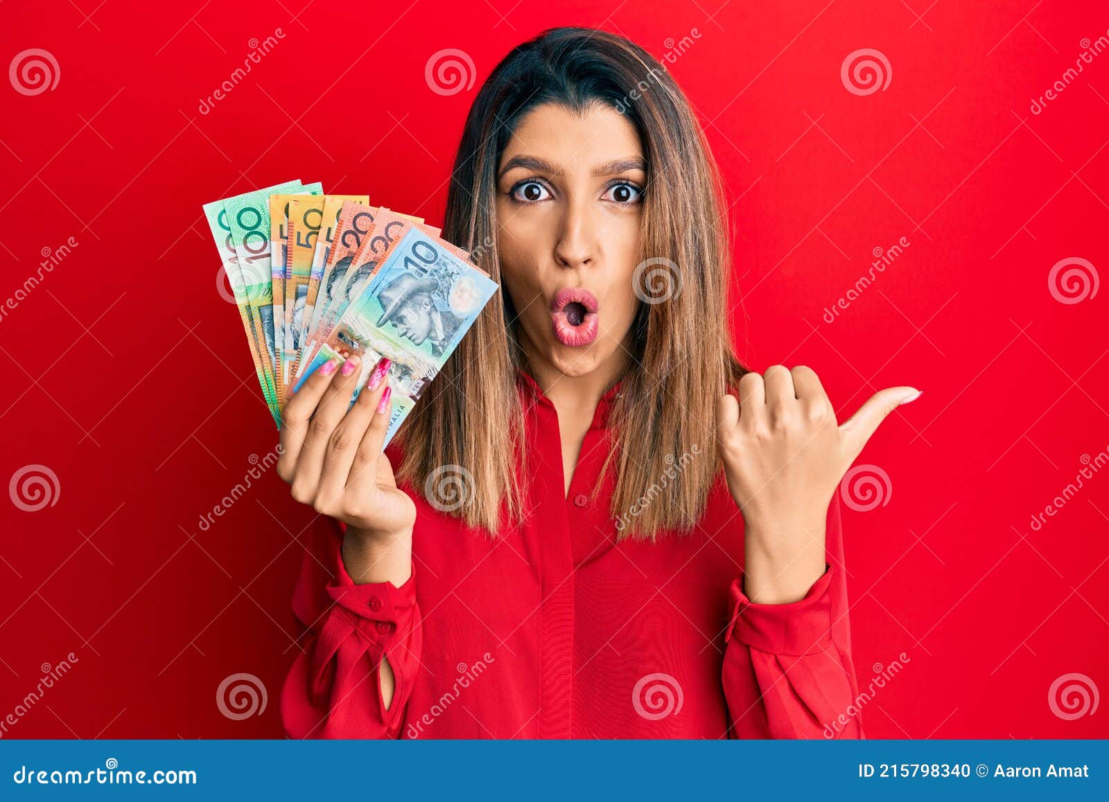 Beautiful Brunette Woman Holding Australian Dollars Surprised Pointing