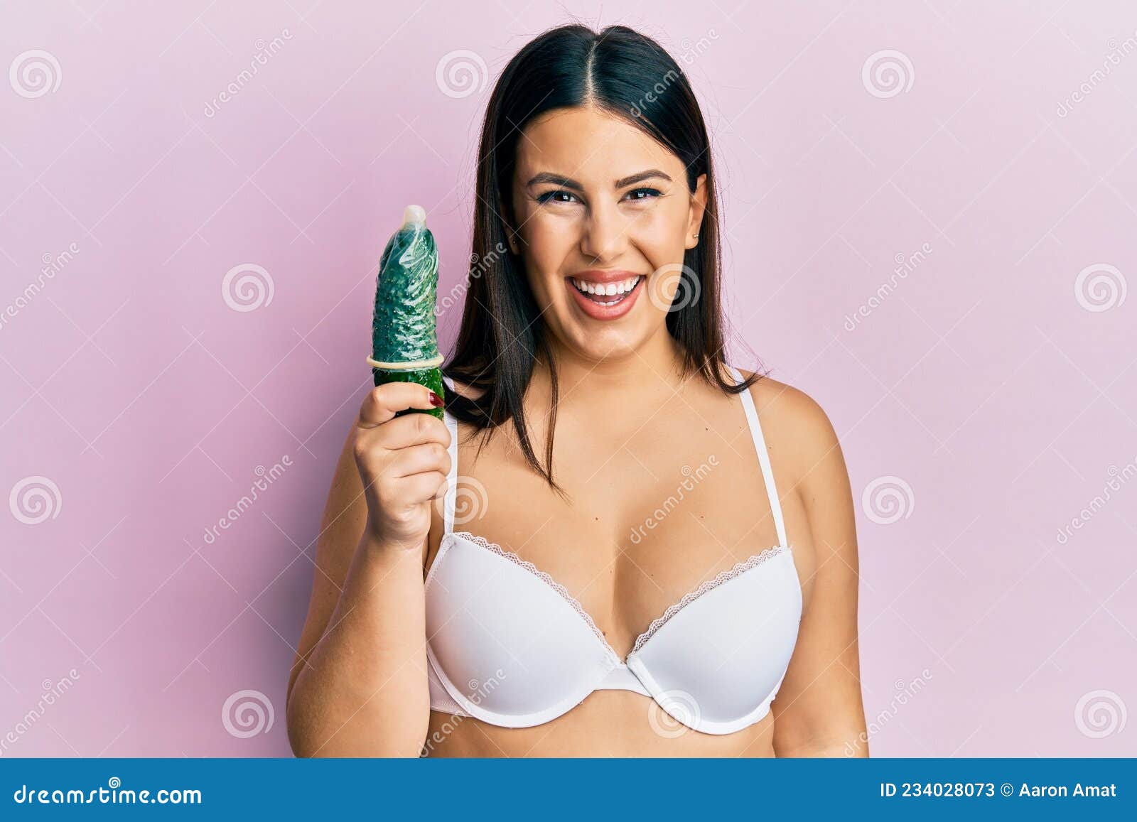 Beautiful Brunette Woman Holding Condom On Cucumber For Sex Education Looking Positive And Happy