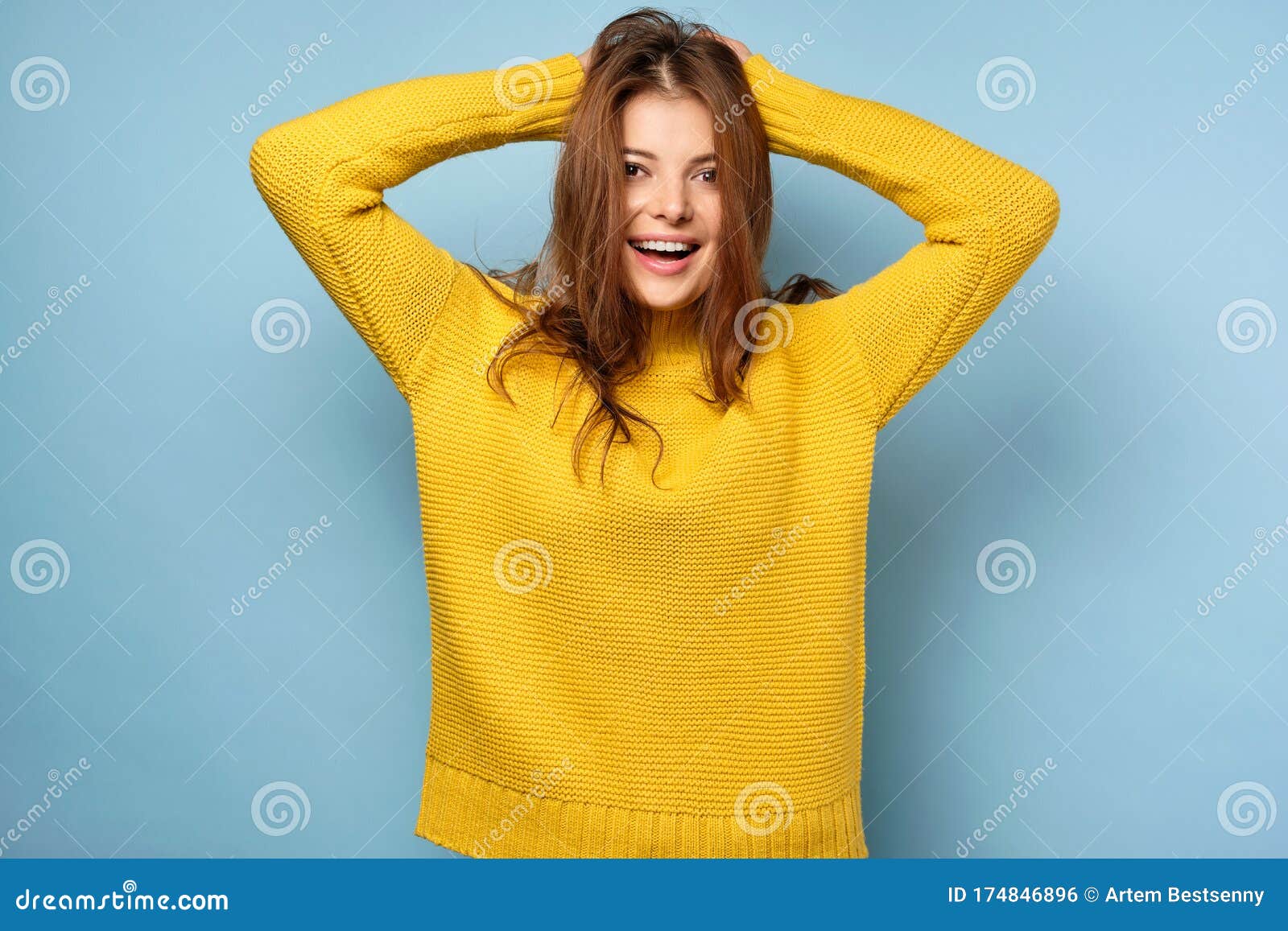 A Beautiful Brunette in a Yellow Sweater Stands on a Blue Background ...