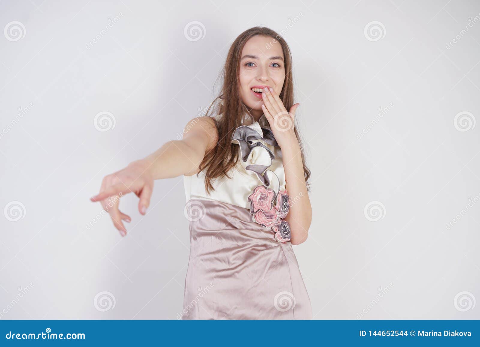 beautiful caucasian teen girl stands in a short evening dress and mocks the interlocutor, humiliating, on a white background in th