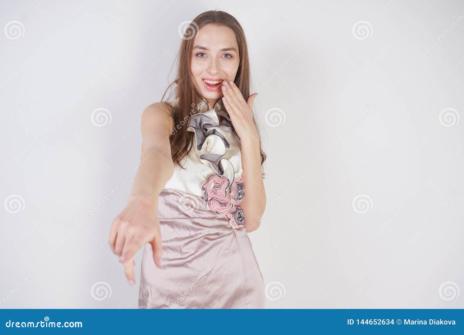 beautiful caucasian teen girl stands in a short evening dress and mocks the interlocutor, humiliating, on a white background in th