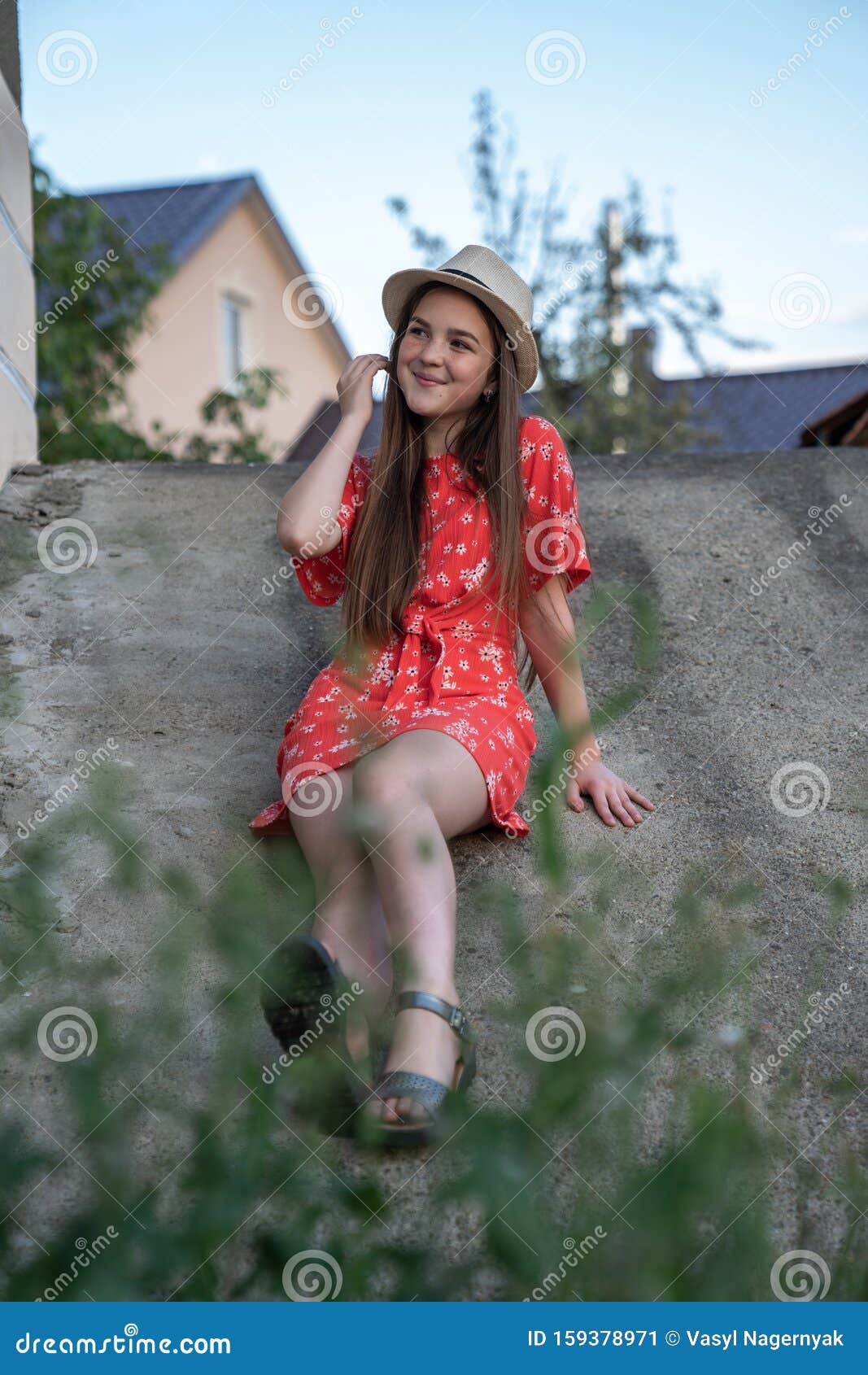 Beautiful Cheerful Teen Girl In Red Dress And Hat Sitting On