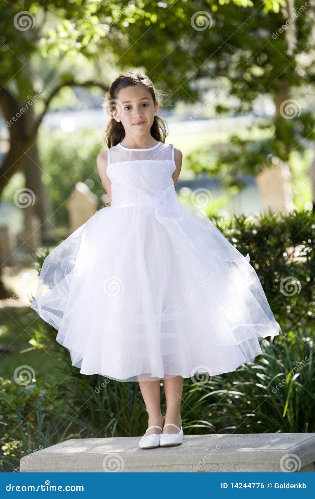 beautiful child in white dress on park bench