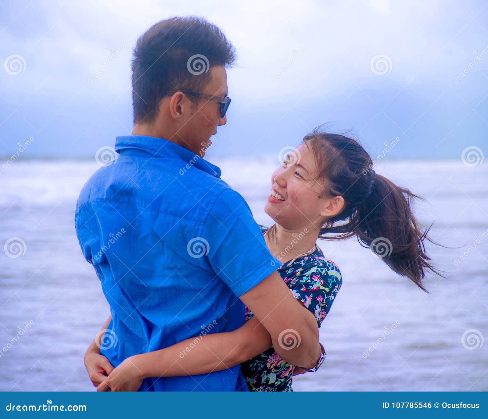 beautiful chinese asian couple with woman hug her boyfriend romantic and cuddle on the beach smiling in dating and romance